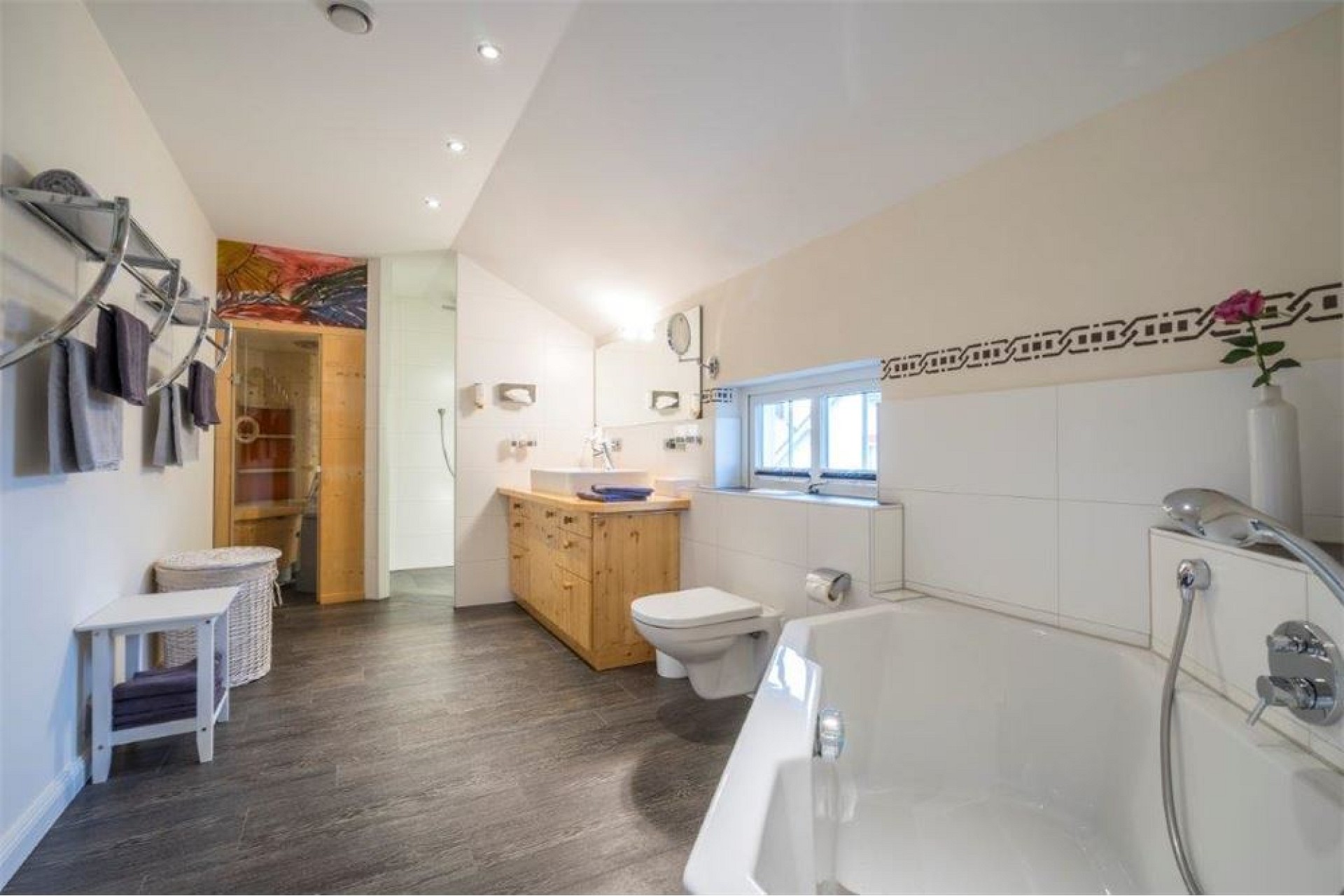 Helles Badezimmer mit Badewanne und Holzkommode
