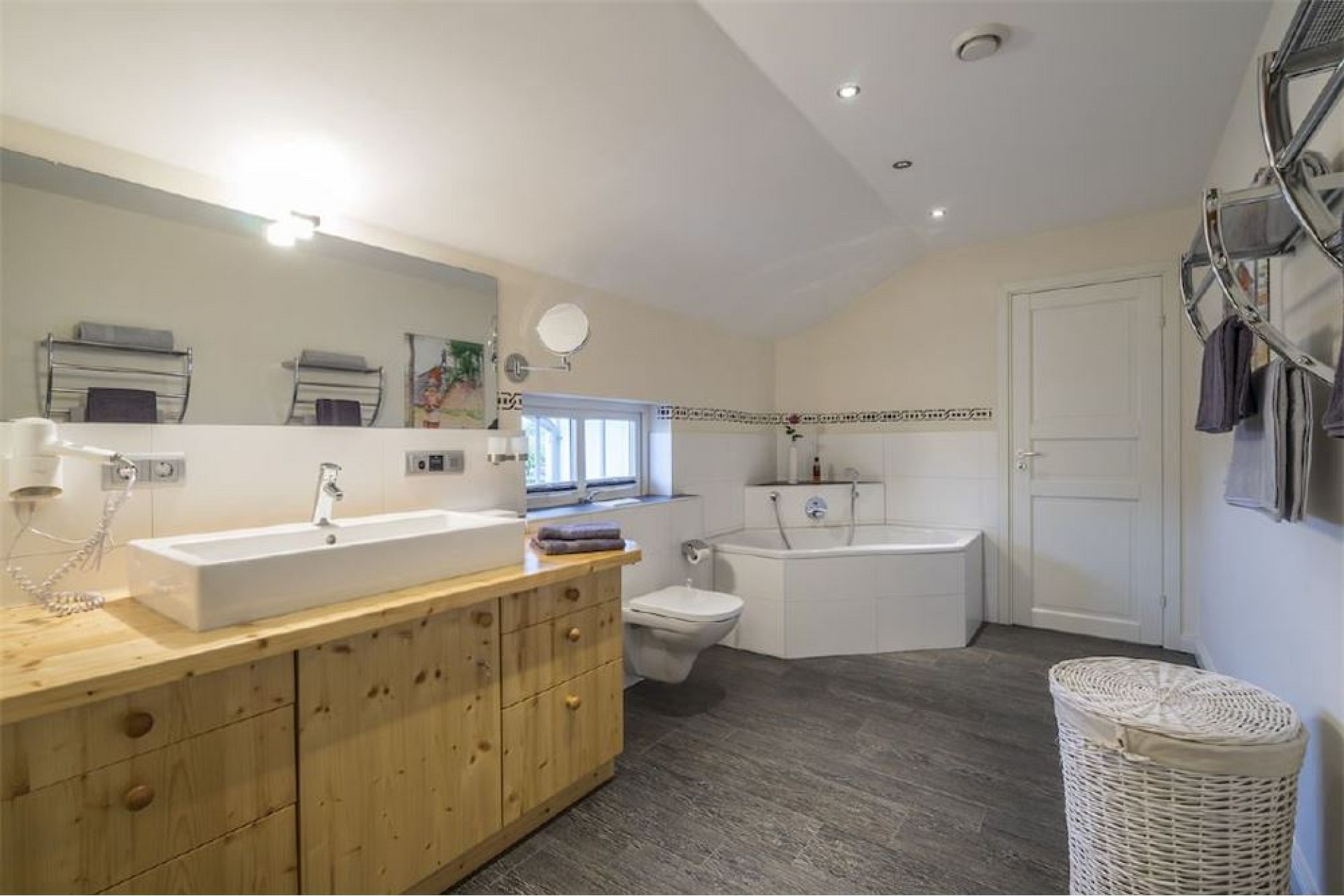 Helles Badezimmer mit Holzwaschtisch und Eckbadewanne