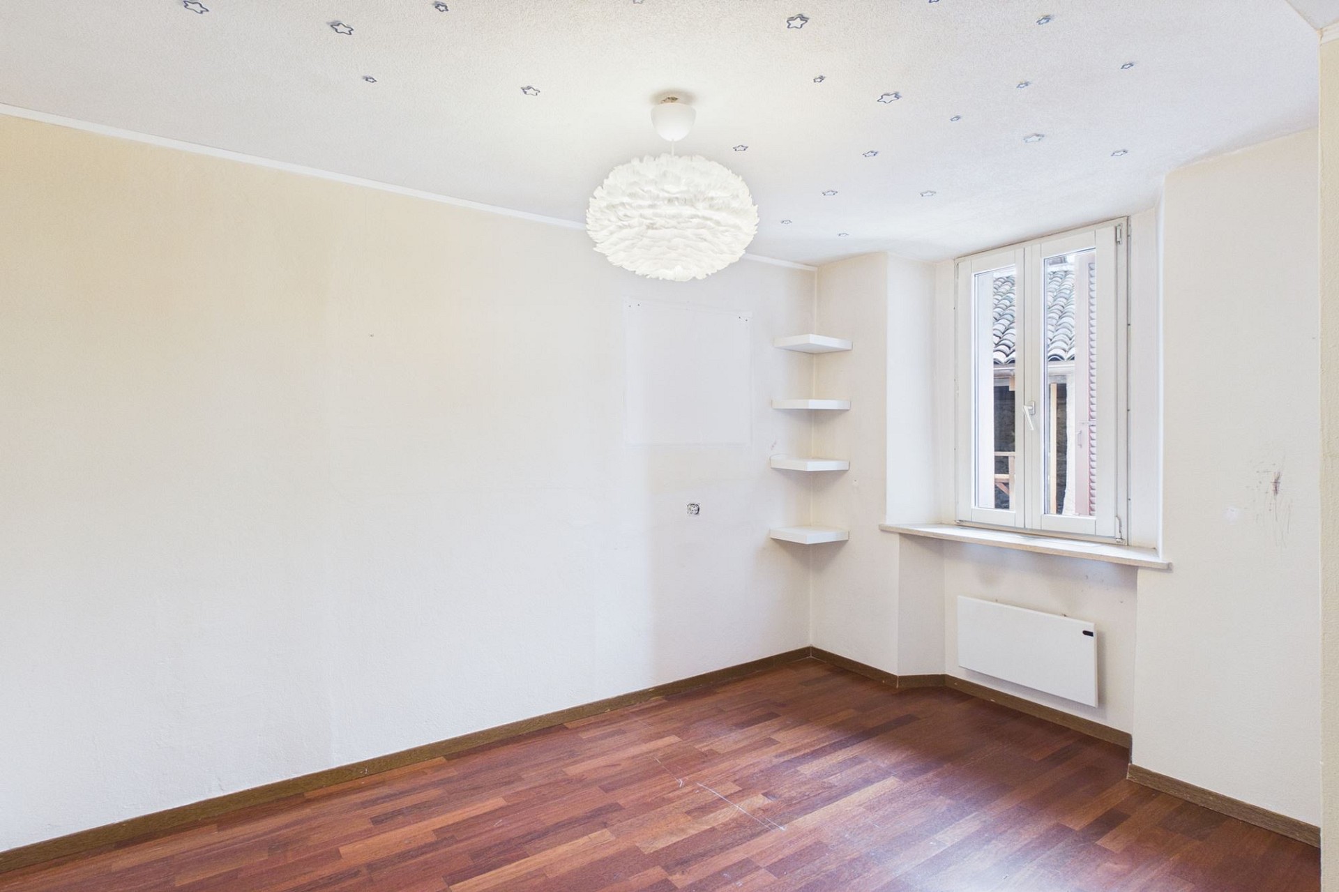 Leerer heller Raum mit Dachfenster und Holzoptikboden