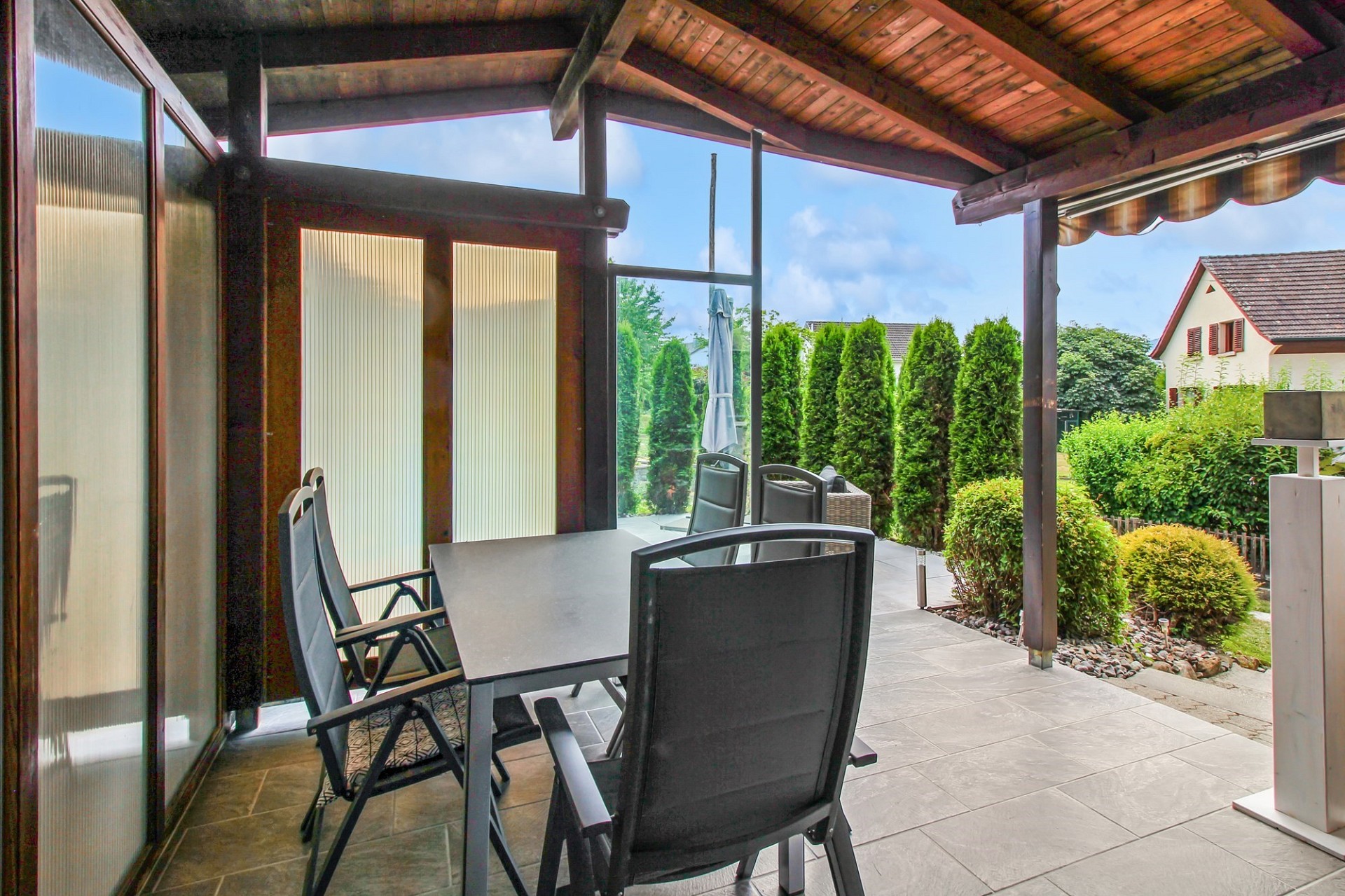 Überdachte Terrasse mit Essbereich und Gartenblick