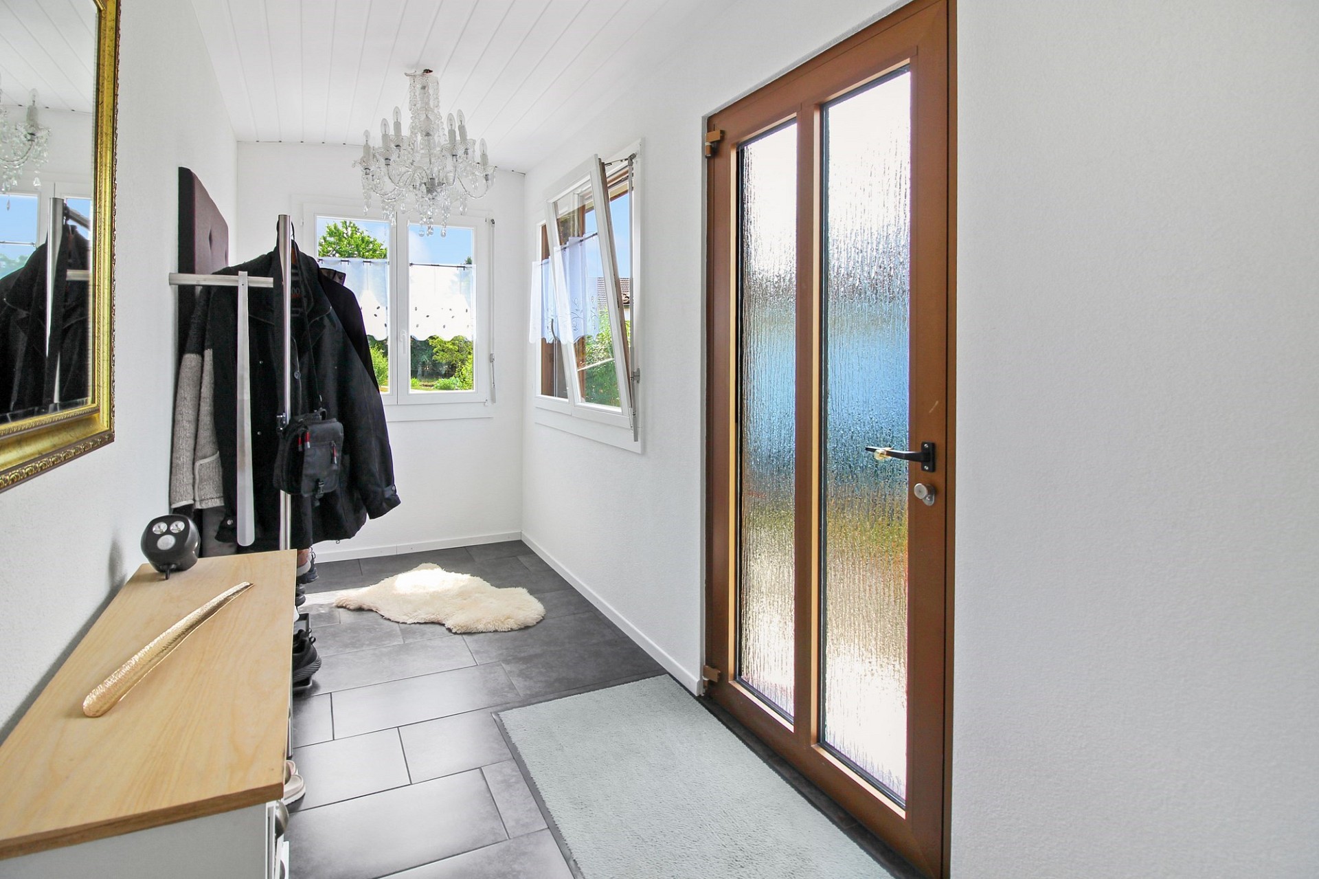Heller Eingangsbereich mit Glastür und Kristalllüster