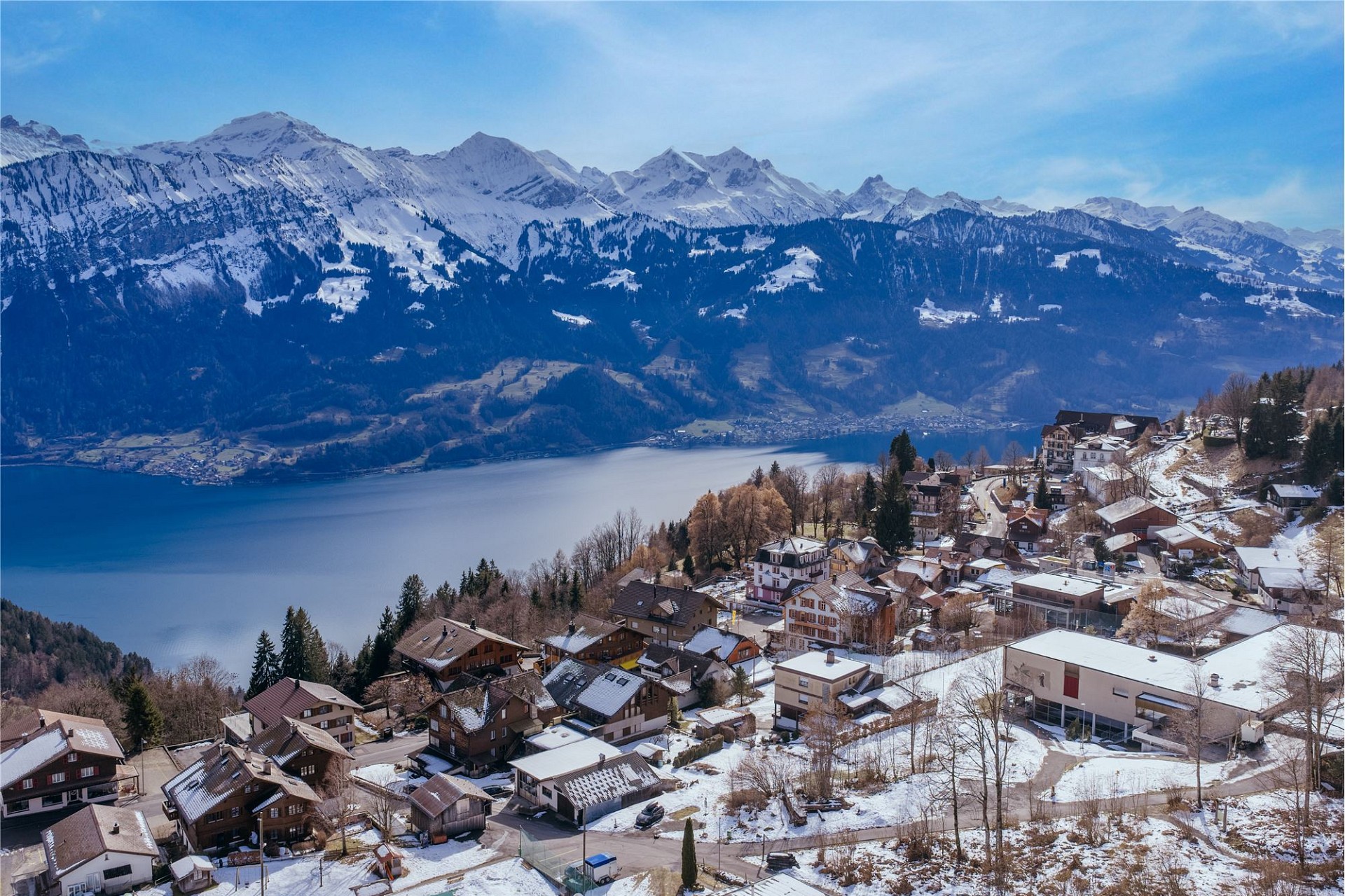 Schneebedecktes Alpenpanorama mit See und Siedlung