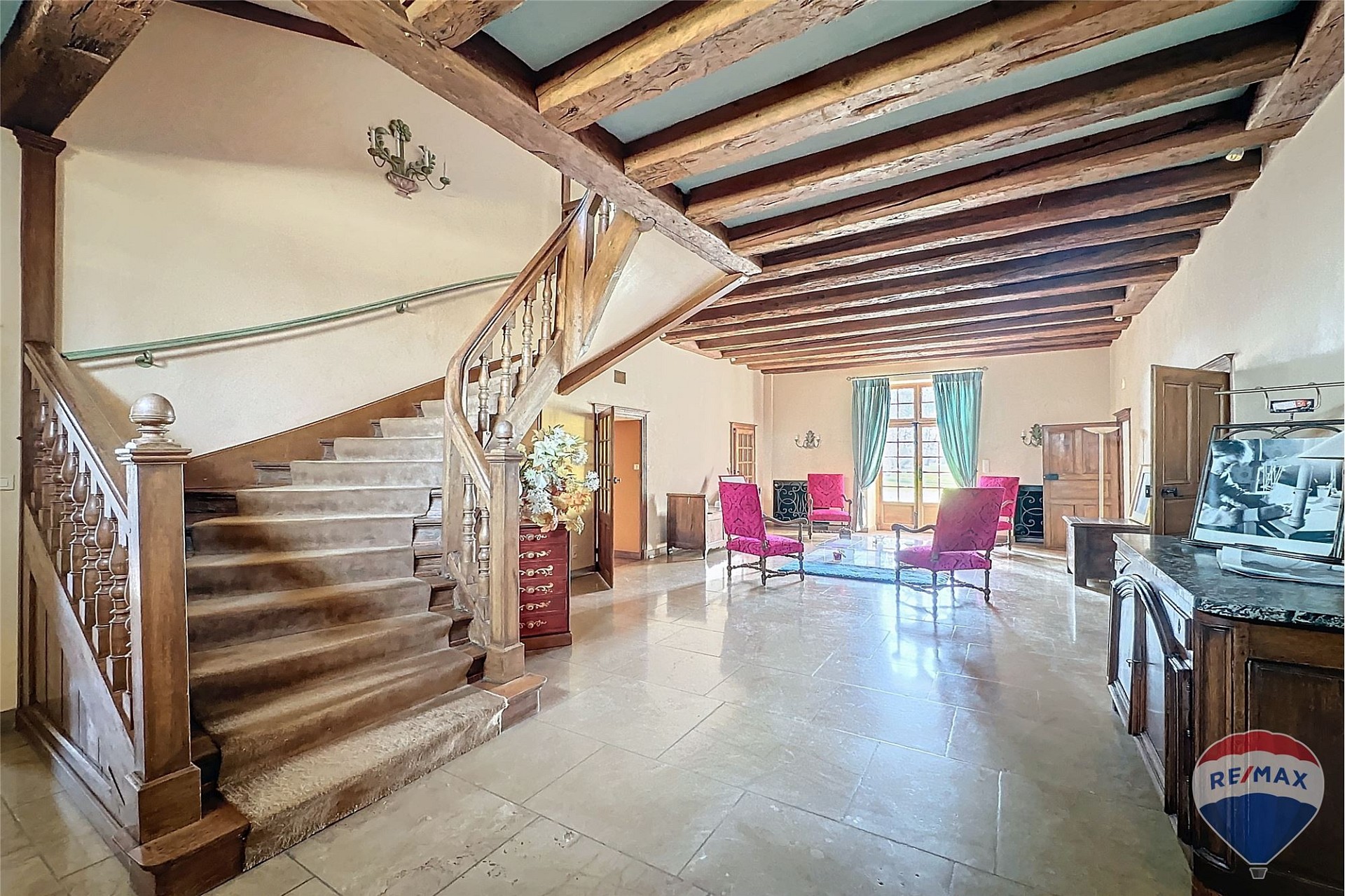 Großer Wohnraum mit Treppe und sichtbaren Holzbalken