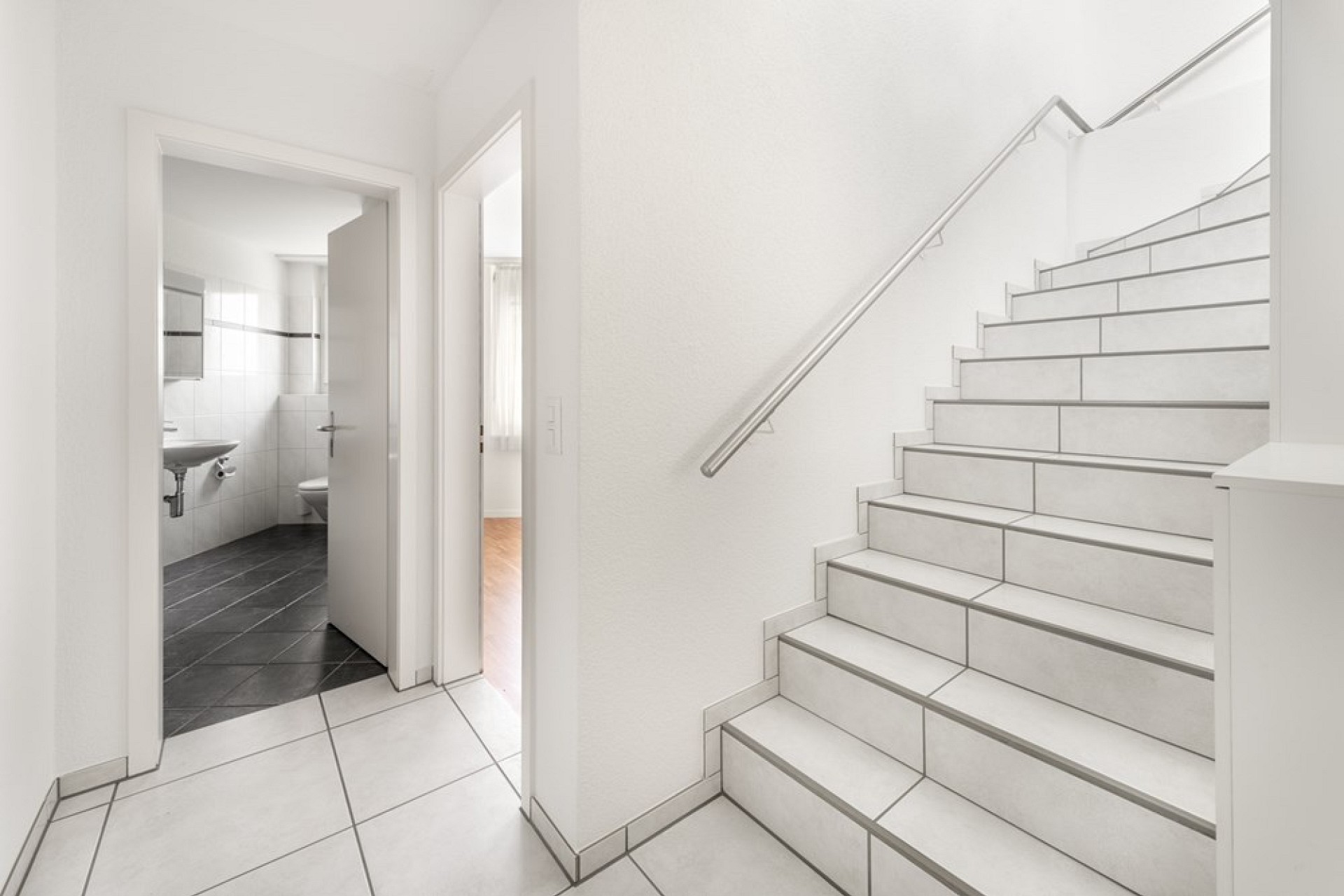 Heller Flur mit Treppe und Blick ins Bad