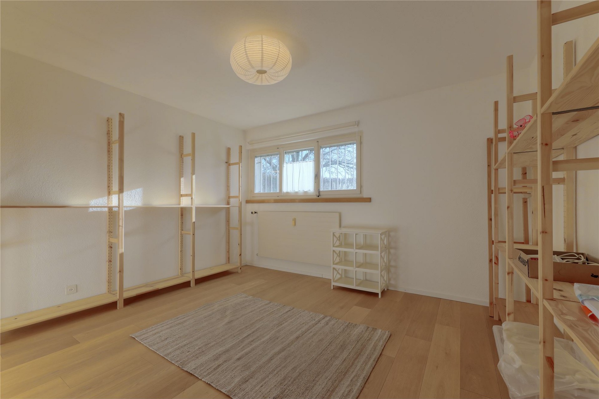 Helles, teilweise eingerichtetes Zimmer mit Holzregalen