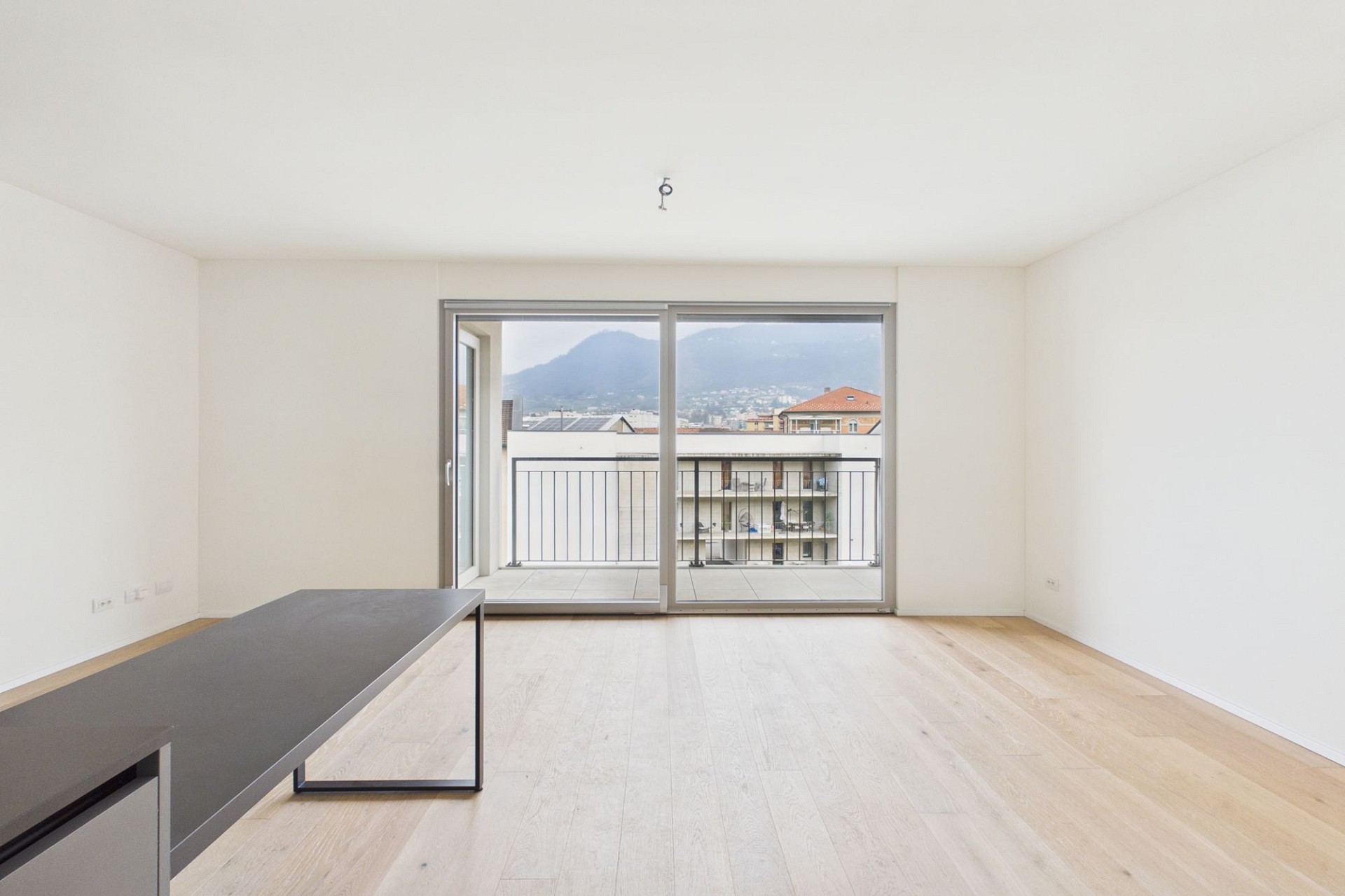 Helles, leeres Wohnzimmer mit Balkon und Bergblick