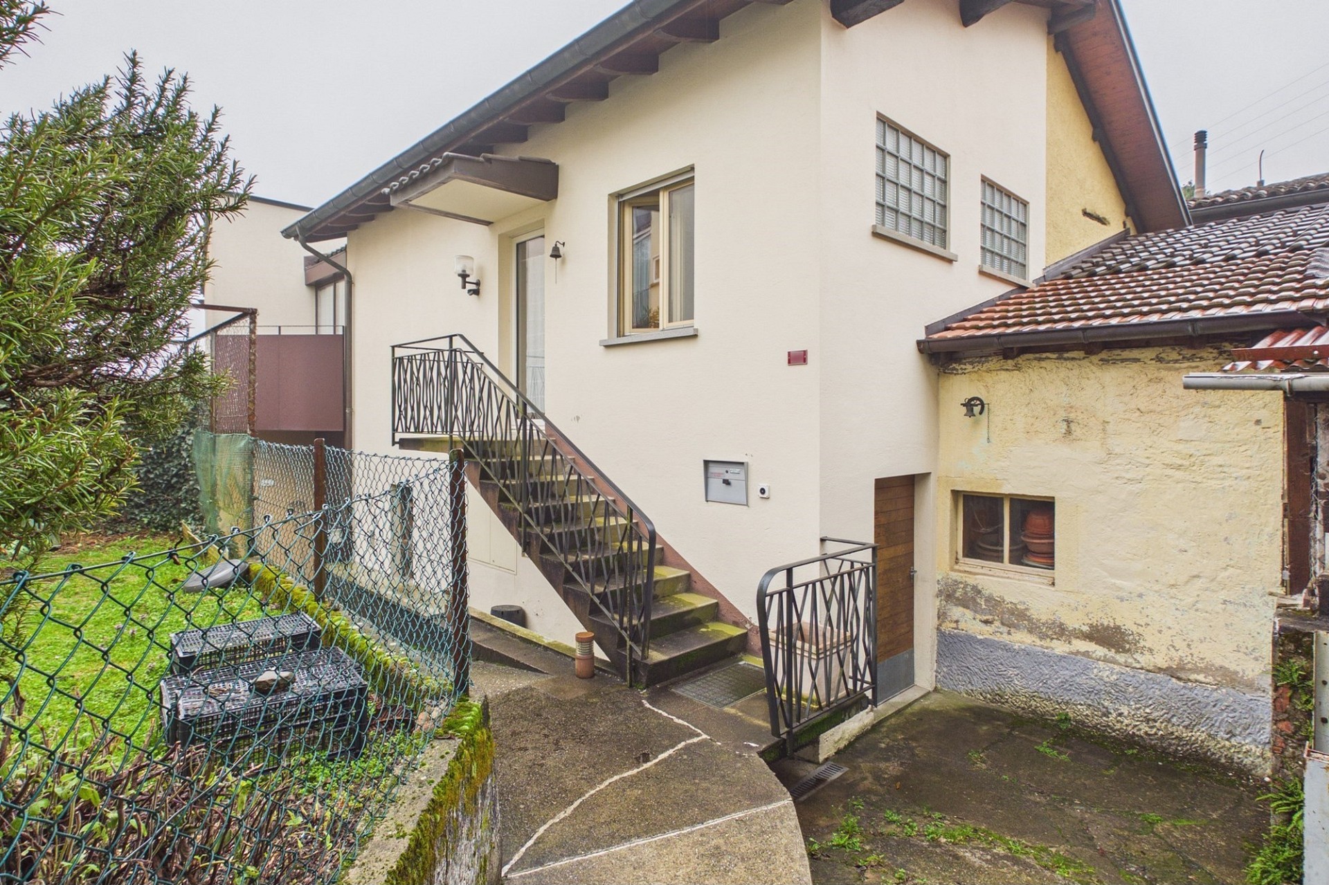 Außenansicht eines älteren Hauses mit Treppe und Garten