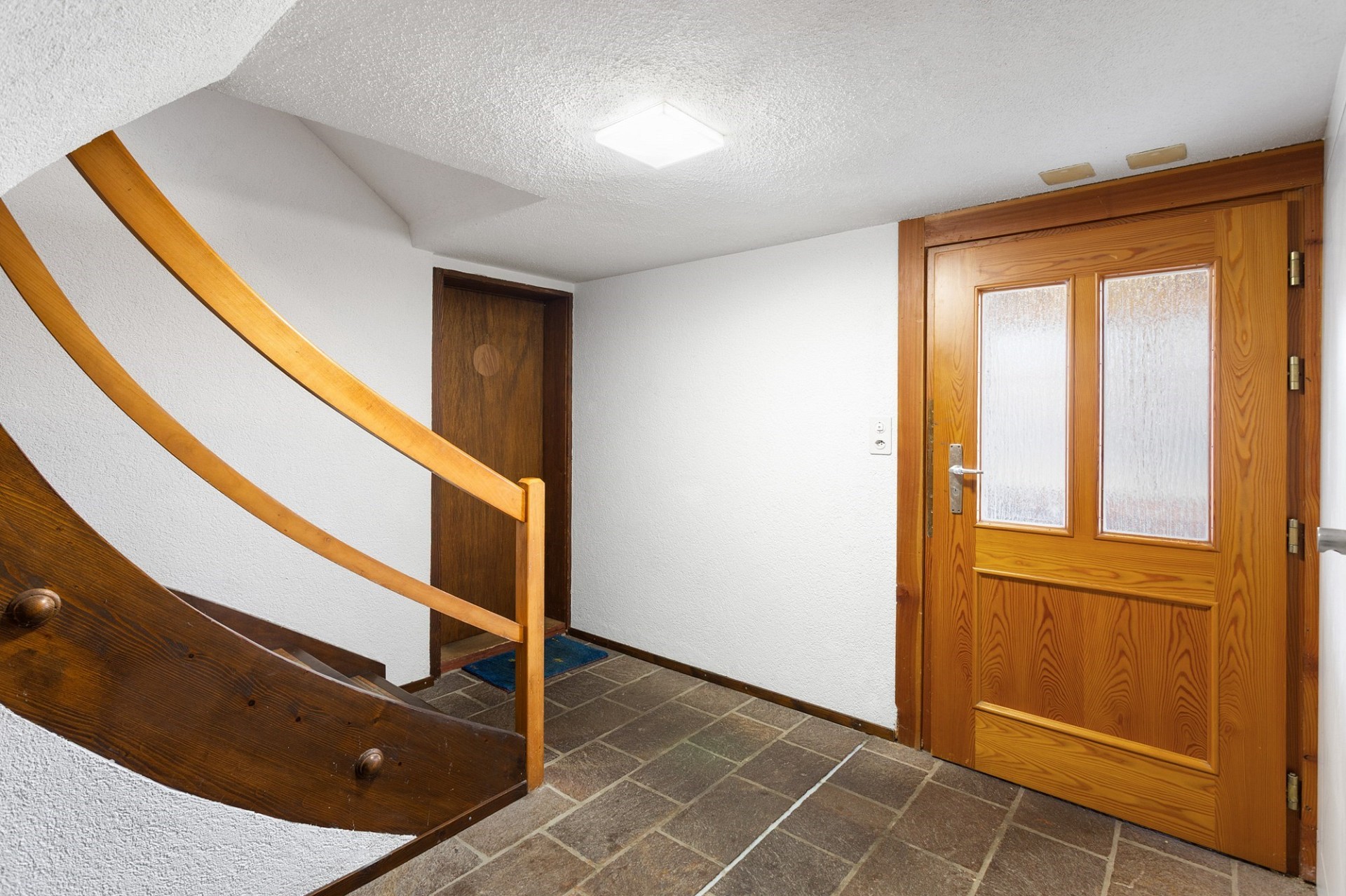 Treppenhaus mit Holztür und Steintreppenboden