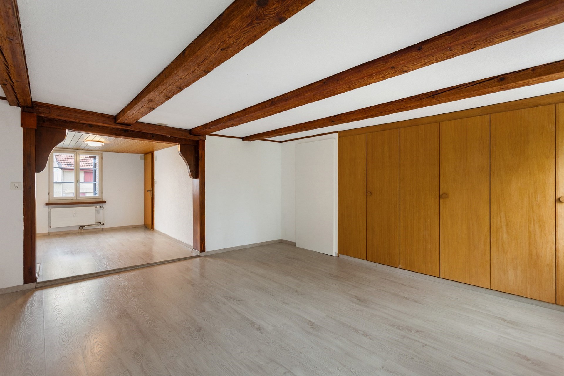 Heller Raum mit sichtbaren Holzbalken und Einbauschrank