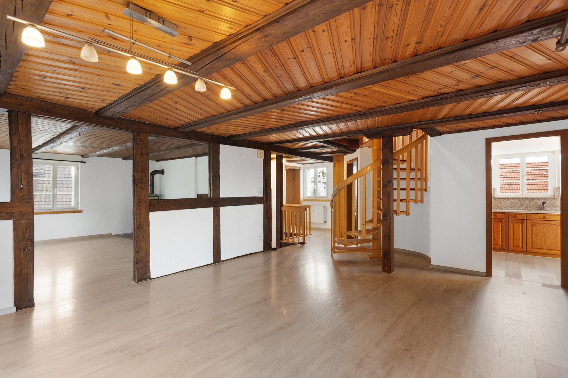 Großer Dachgeschossraum mit sichtbarer Holzdecke und Wendeltreppe