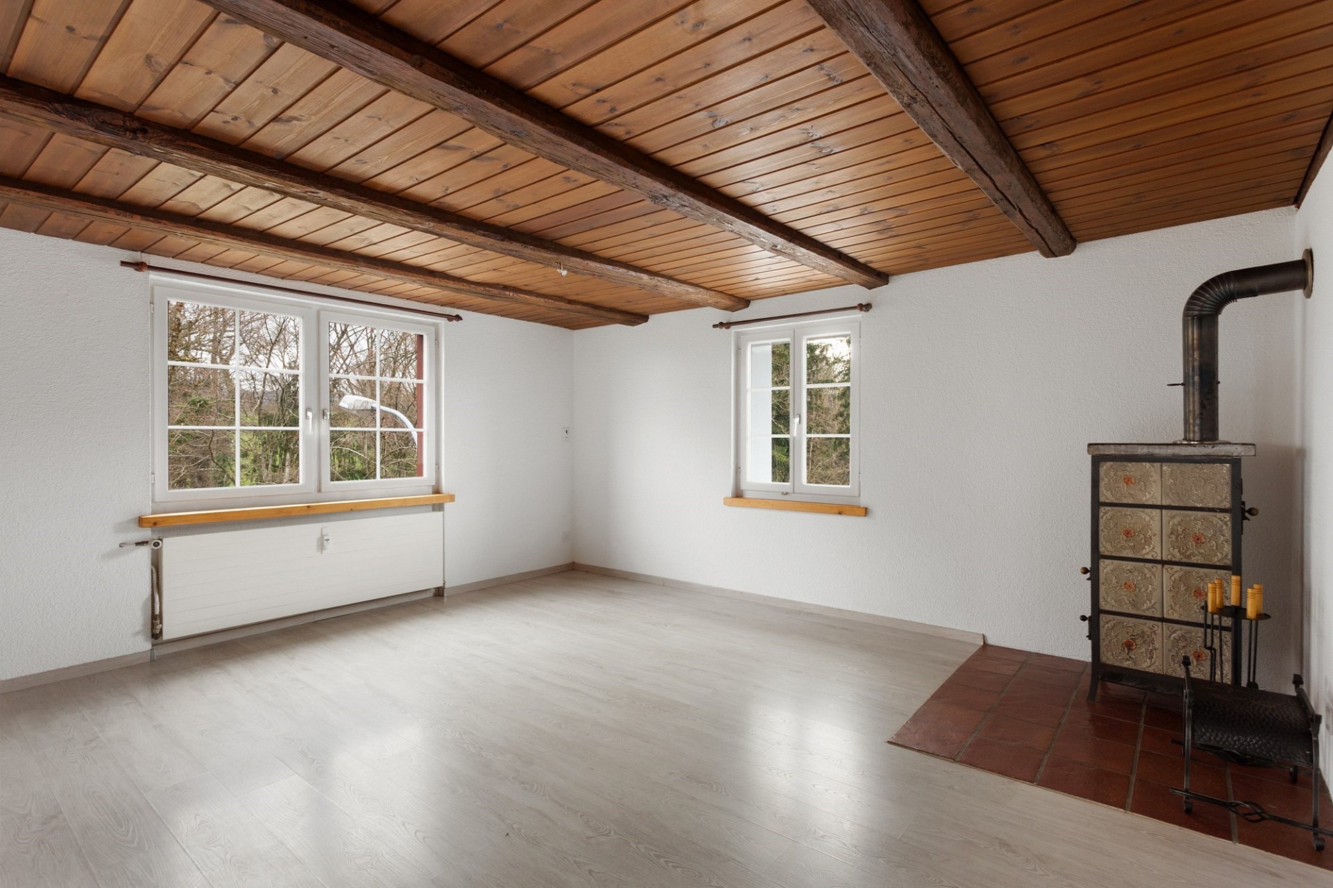 Leerer Wohnraum mit Holzdecke und Kaminofen