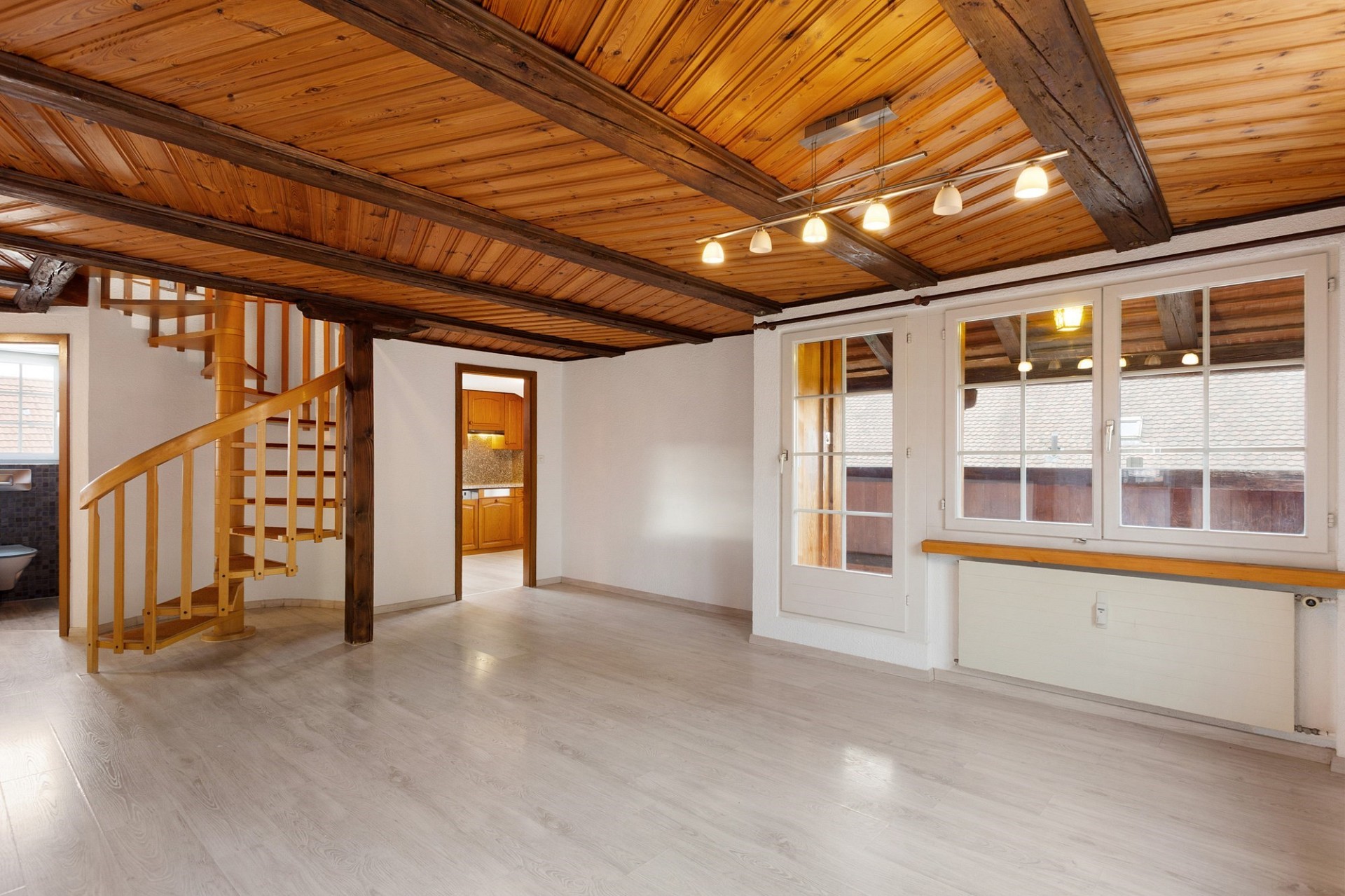 Heller Wohnraum mit Holzdecke und Wendeltreppe