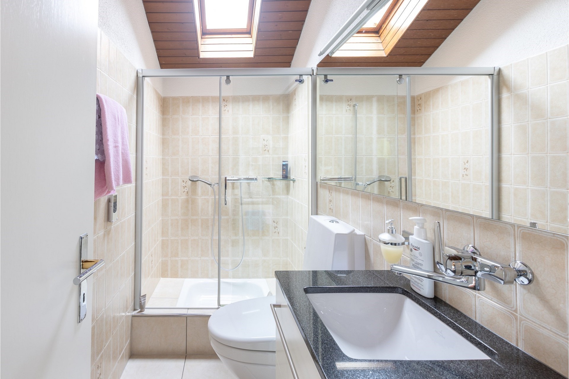 Helles Badezimmer mit Dachfenstern und Glasduschkabine