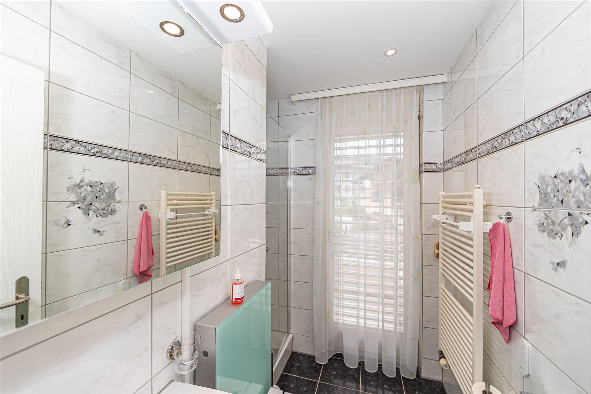 Helles Badezimmer mit gefliesten Wänden und Fenster