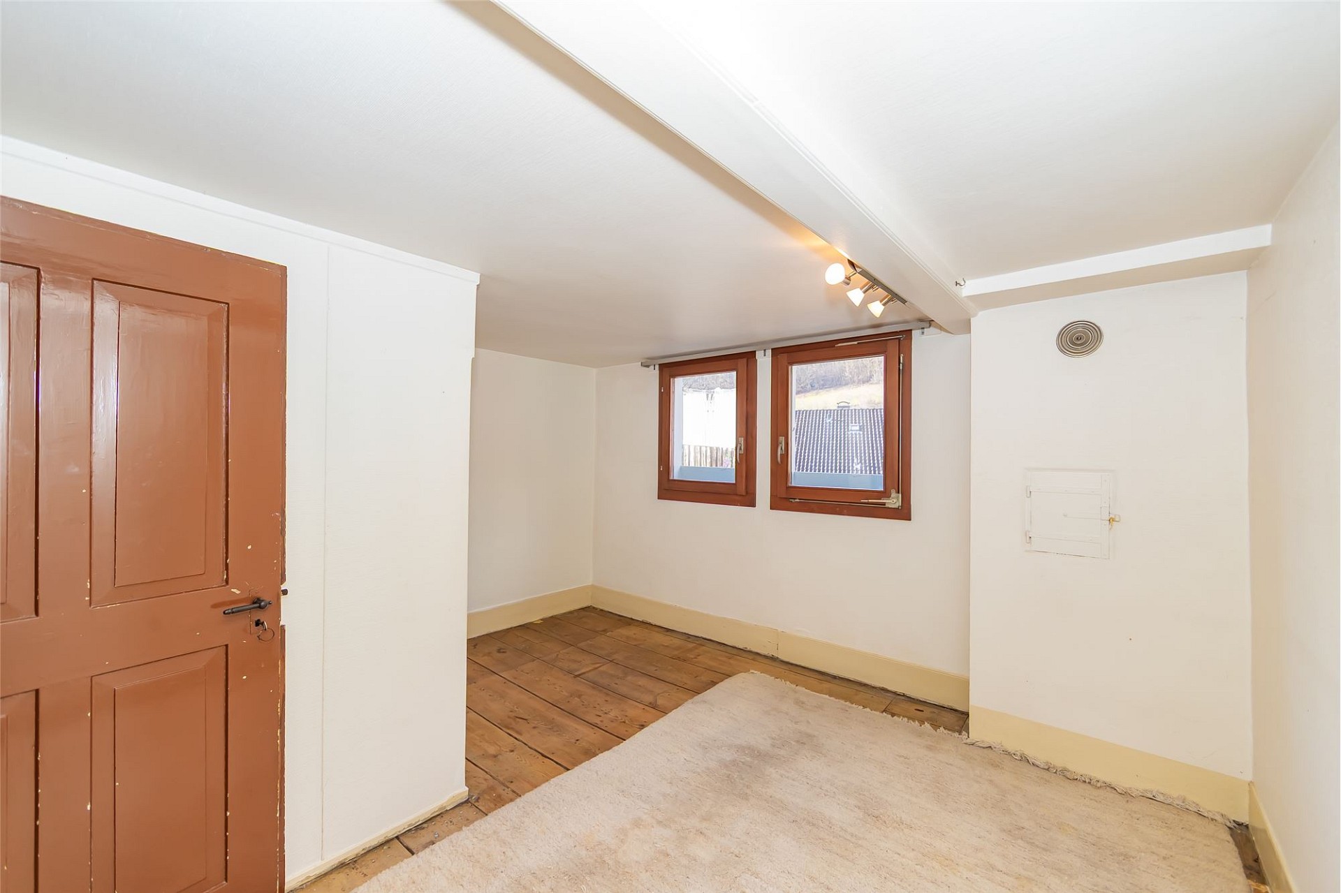 Kleiner Dachgeschossraum mit Holzfenstern