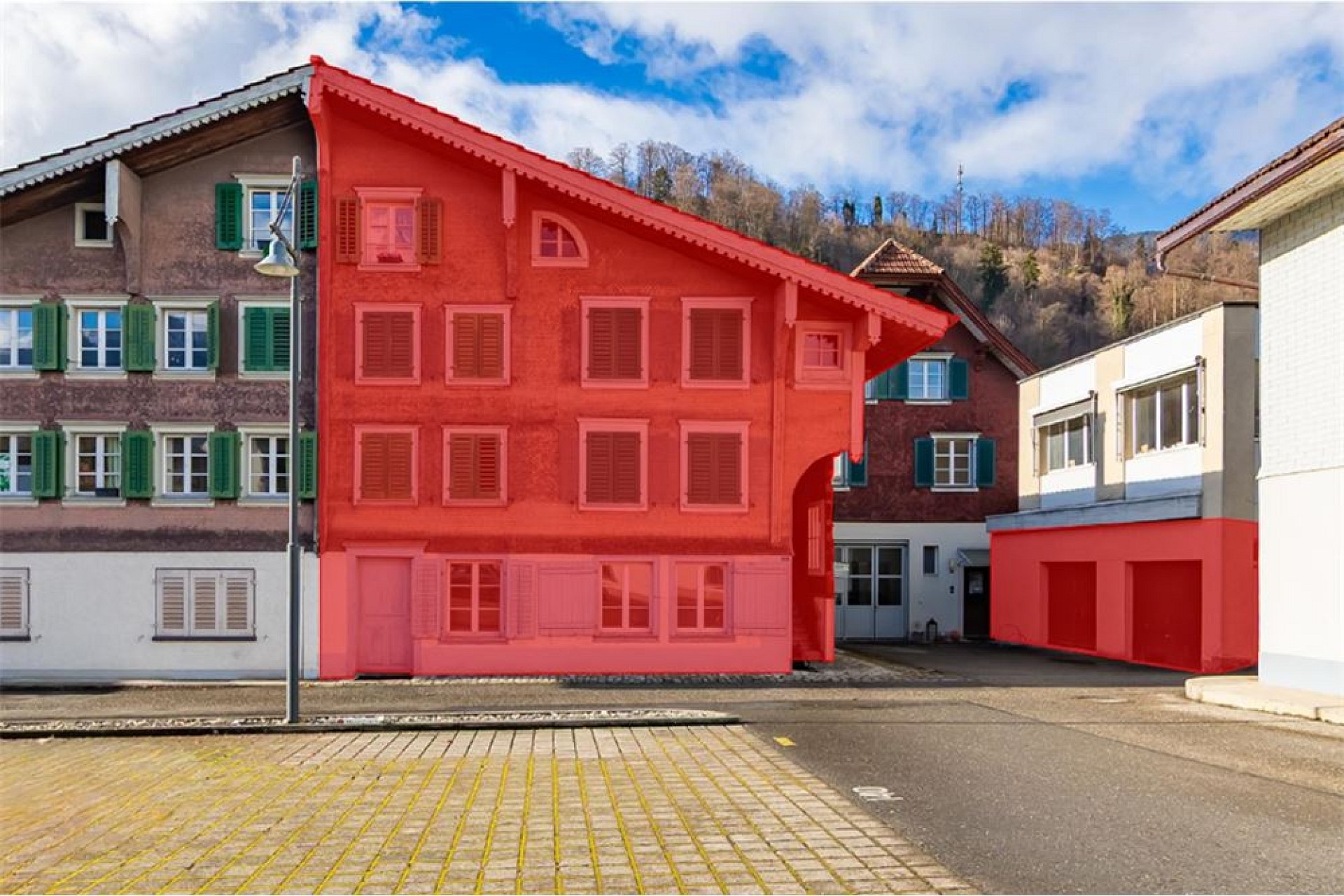 Mehrere Wohnhäuser in einem alpinen Dorf, zentrales Haus markiert