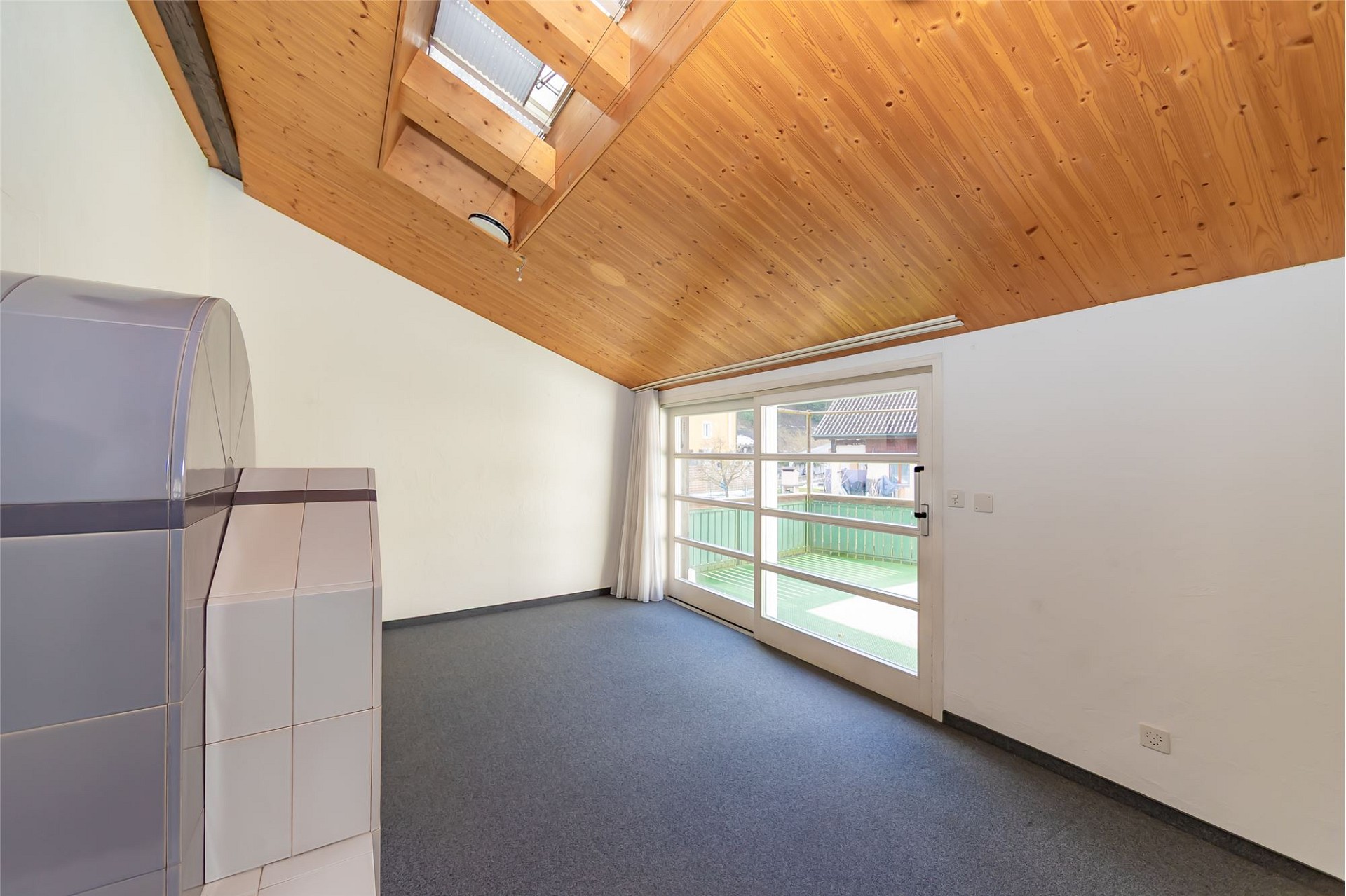 Dachgeschossraum mit Holzdecke und Balkonzugang
