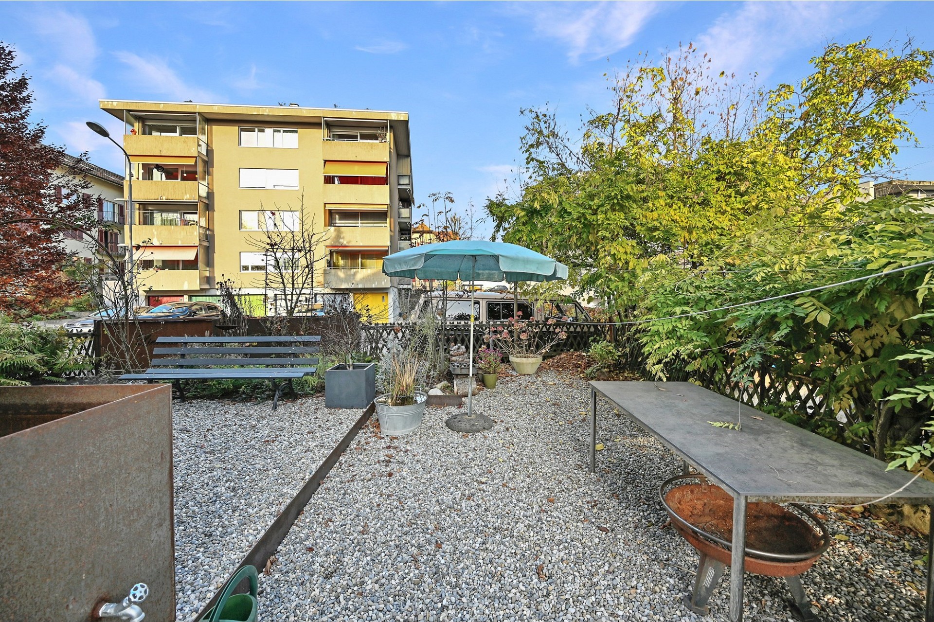 Gemeinschaftsgarten mit Sitzbereich vor einem Mehrfamilienhaus