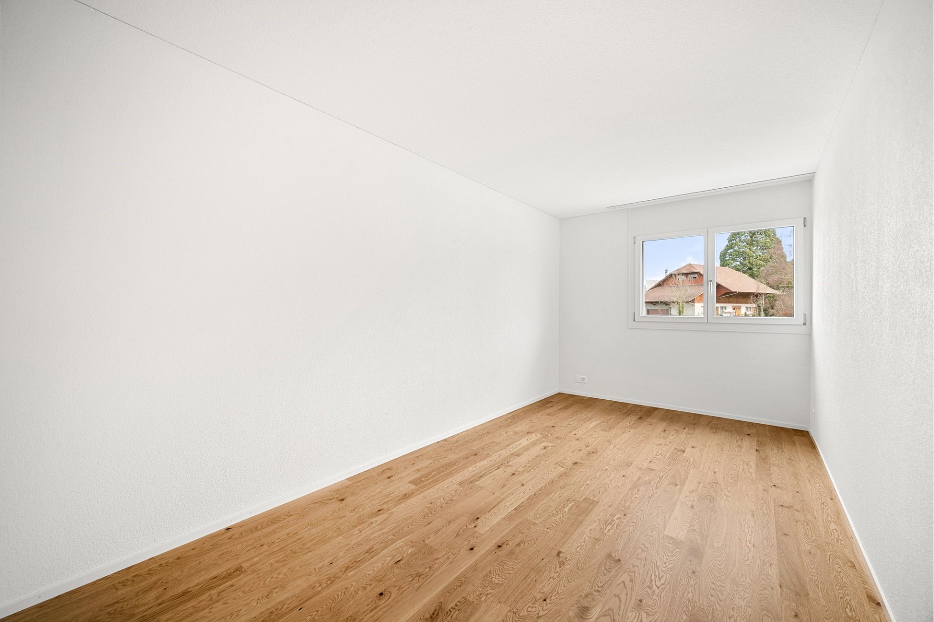 Heller leerer Raum mit Holzfußboden und Fenster