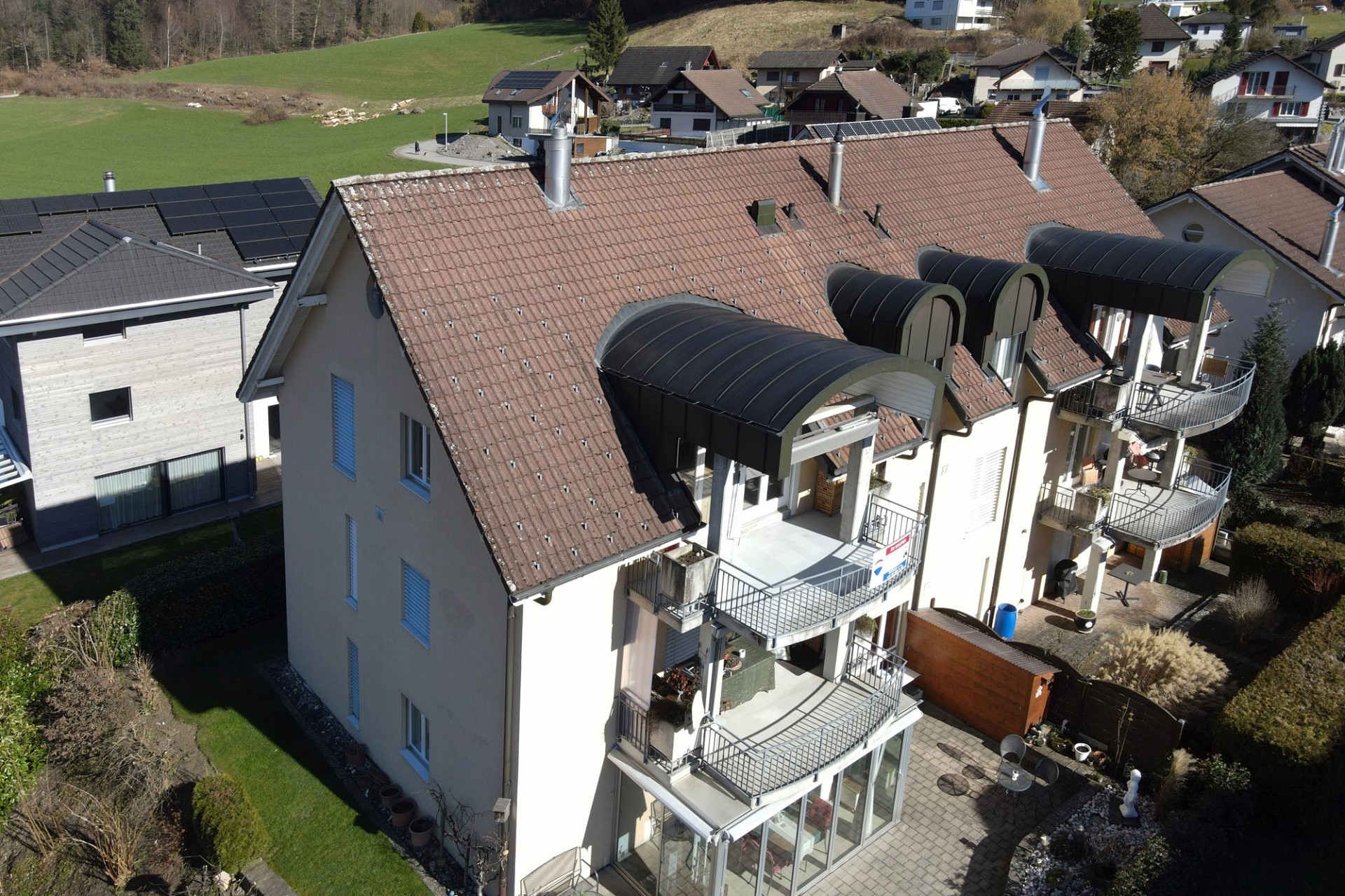 Drohnenaufnahme eines Mehrfamilienhauses mit Balkonen und umliegenden Wohnhäusern