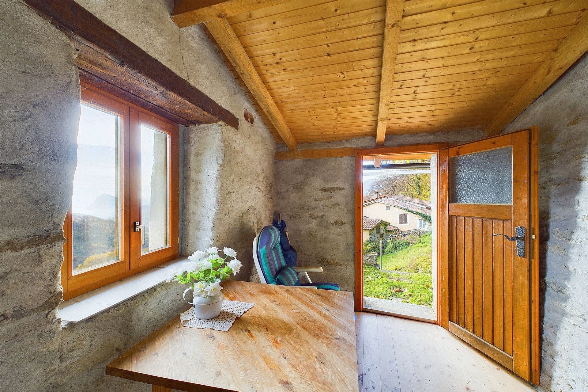 Rustikaler kleiner Raum mit Holztür und Bergblick