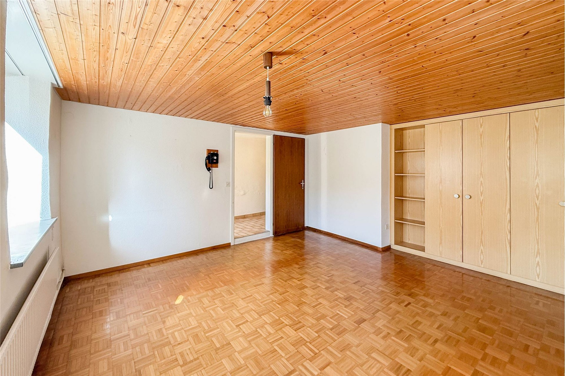 Leeres Zimmer mit Holzdecke und Parkettboden