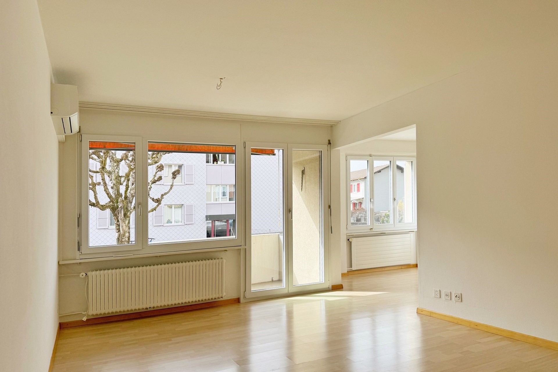 Heller leerer Wohnraum mit Balkon- und Fensterfront