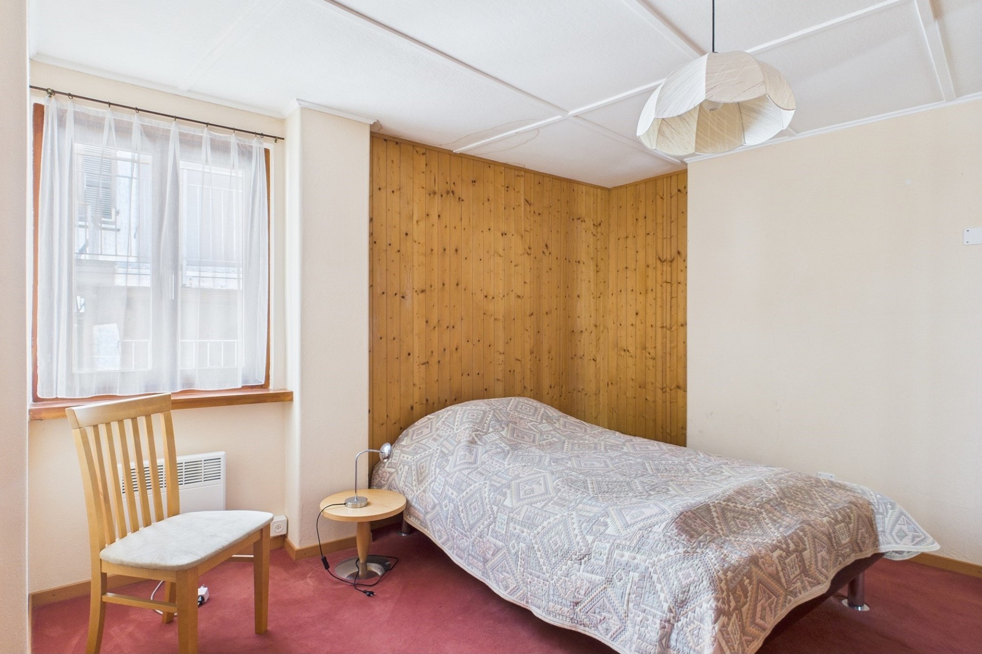 Einfaches Schlafzimmer mit Fenster und Bett