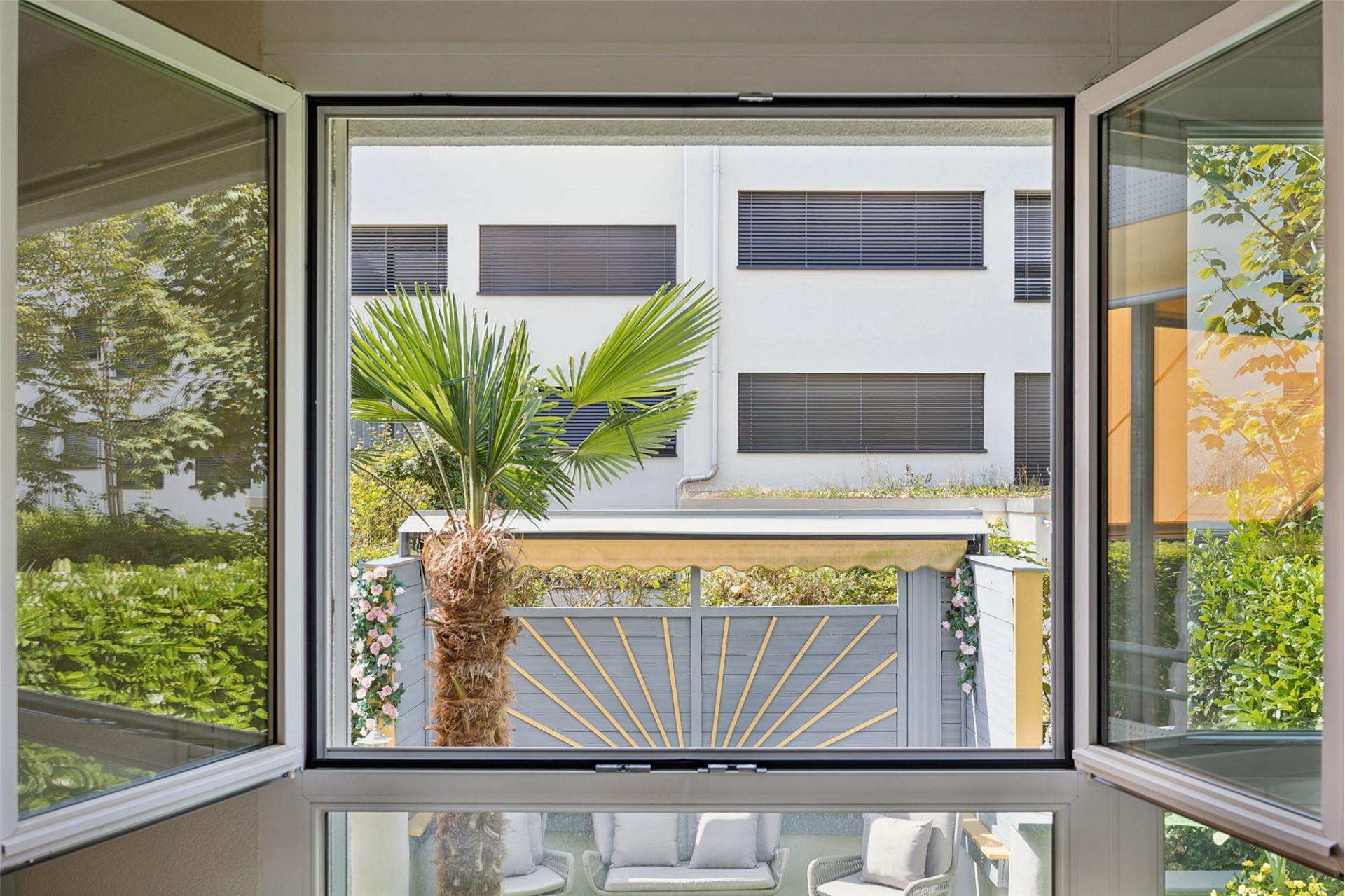 Blick durch ein geöffnetes Fenster auf Innenhof und Balkon