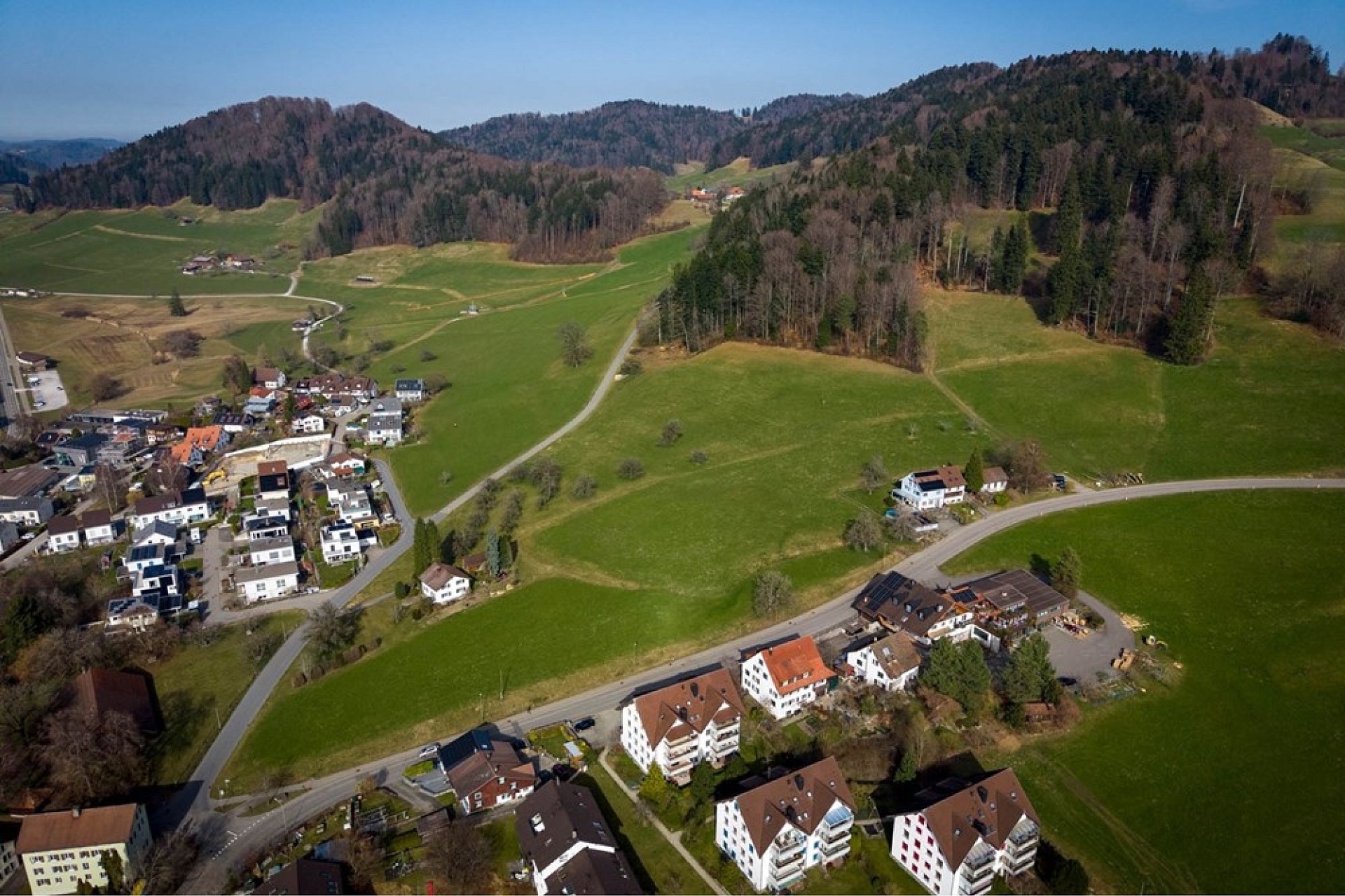 Luftaufnahme einer ländlichen Siedlung in alpiner Landschaft