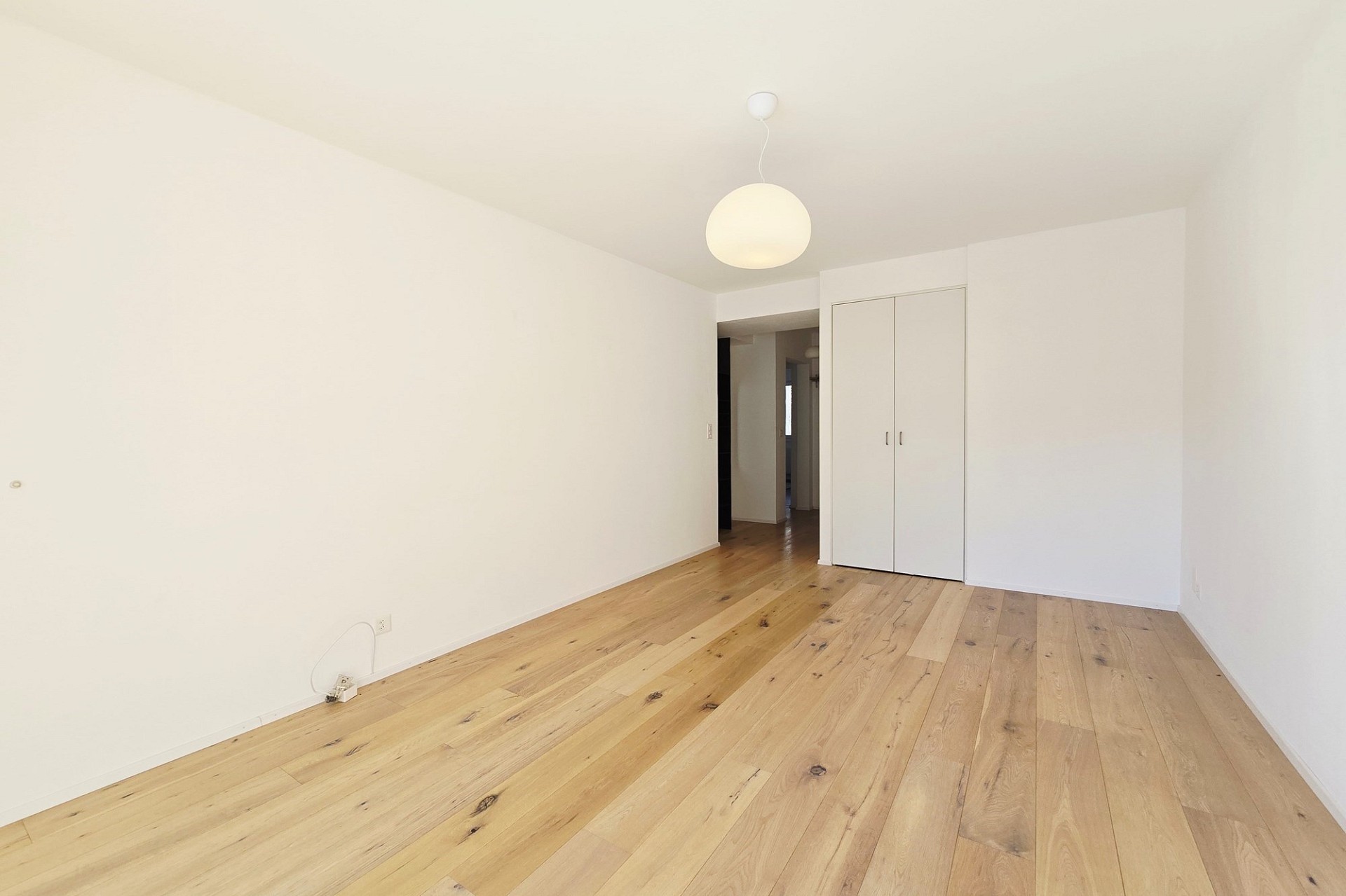 Helles, leeres Schlafzimmer mit Holzboden