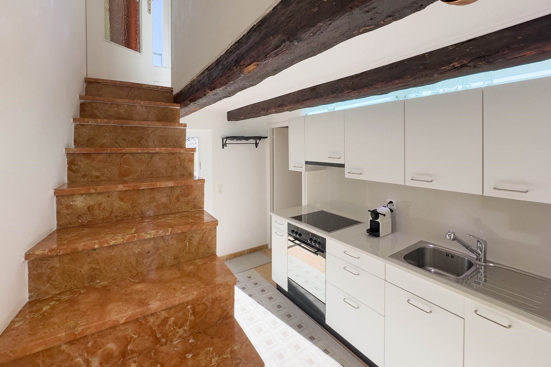 Kleine Küche mit Treppe und Holzbalken
