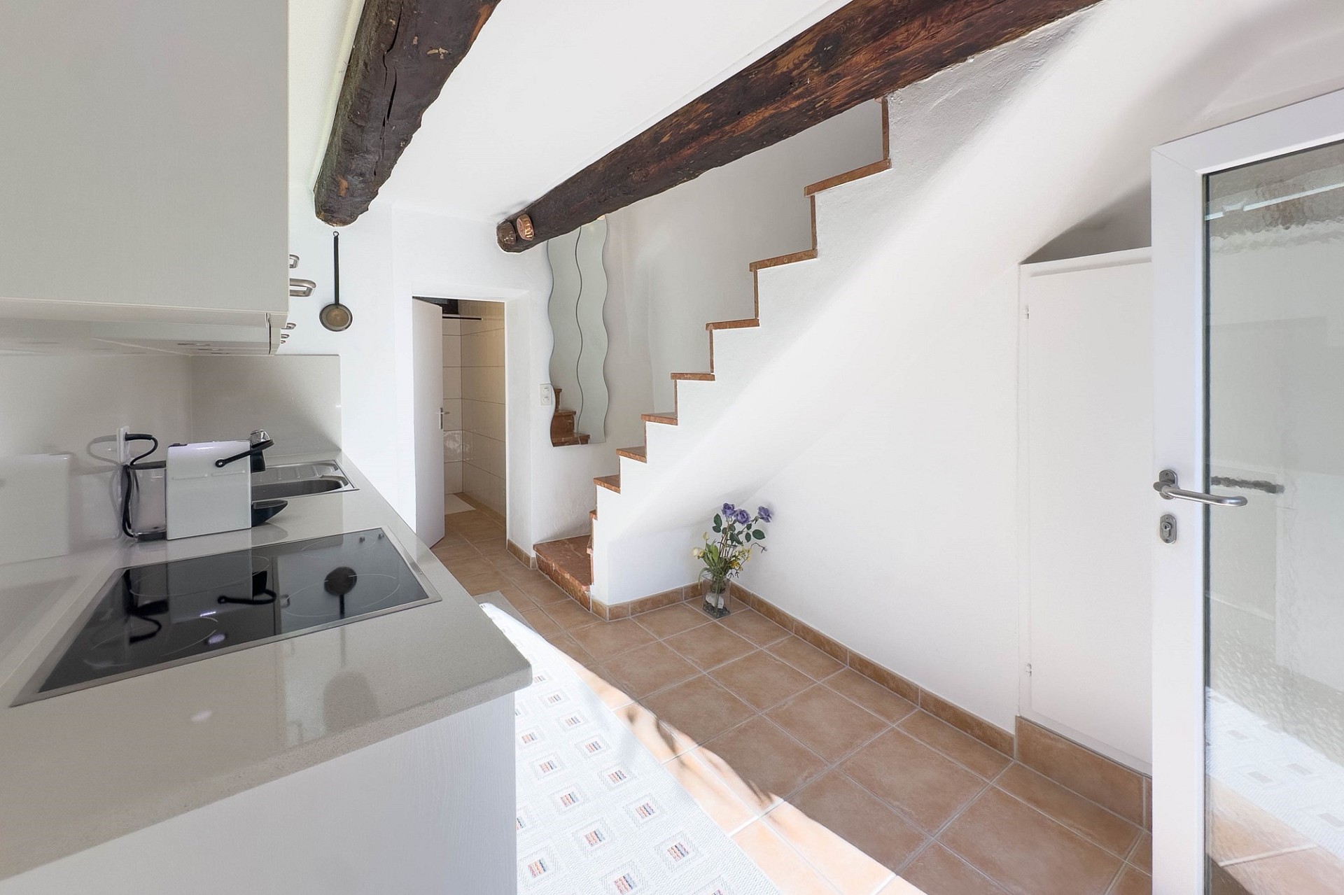 Helle Küche mit sichtbarer Holzdecke und Treppe
