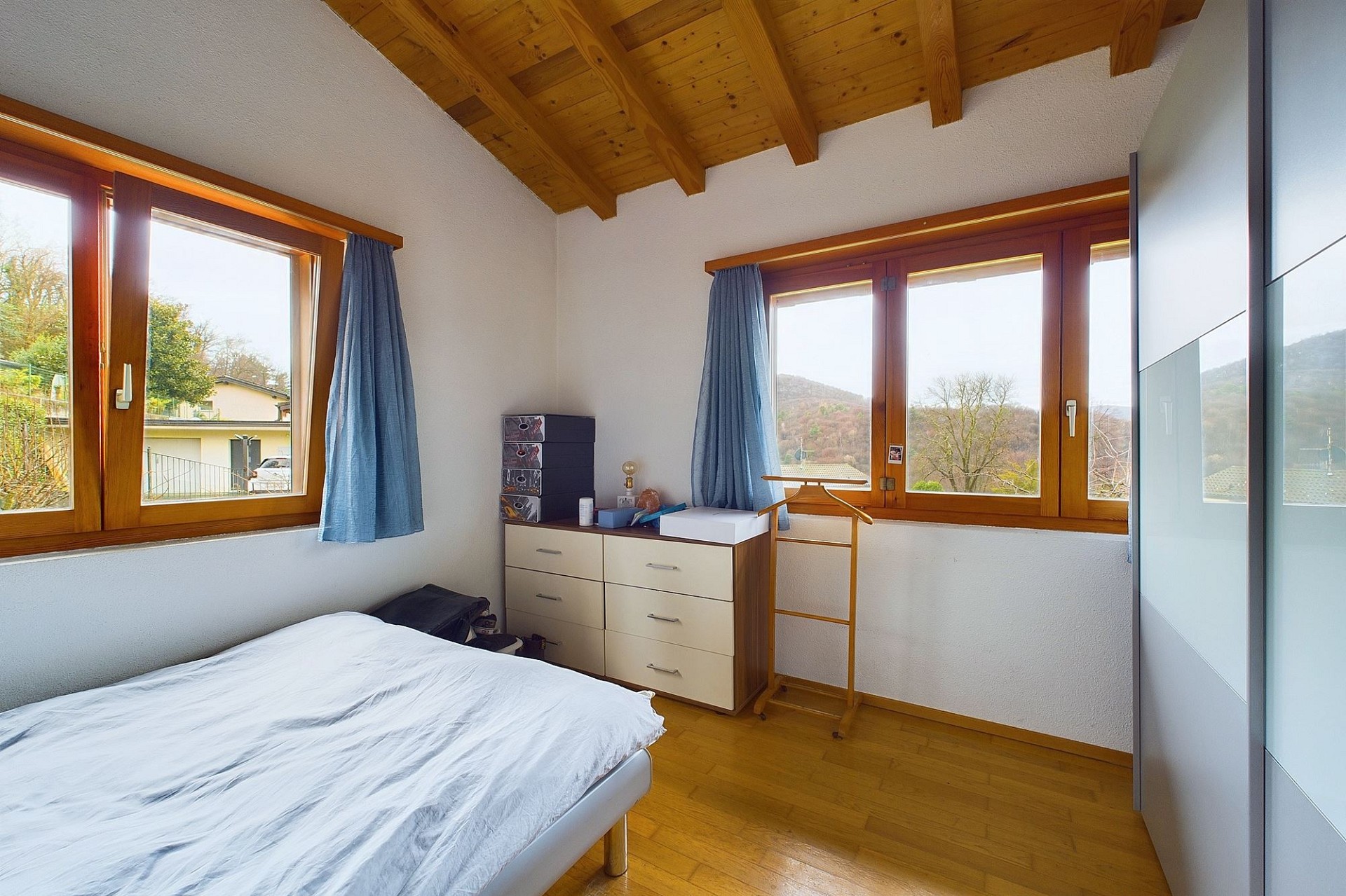 Helles Schlafzimmer mit Holzdecke und Bergblick