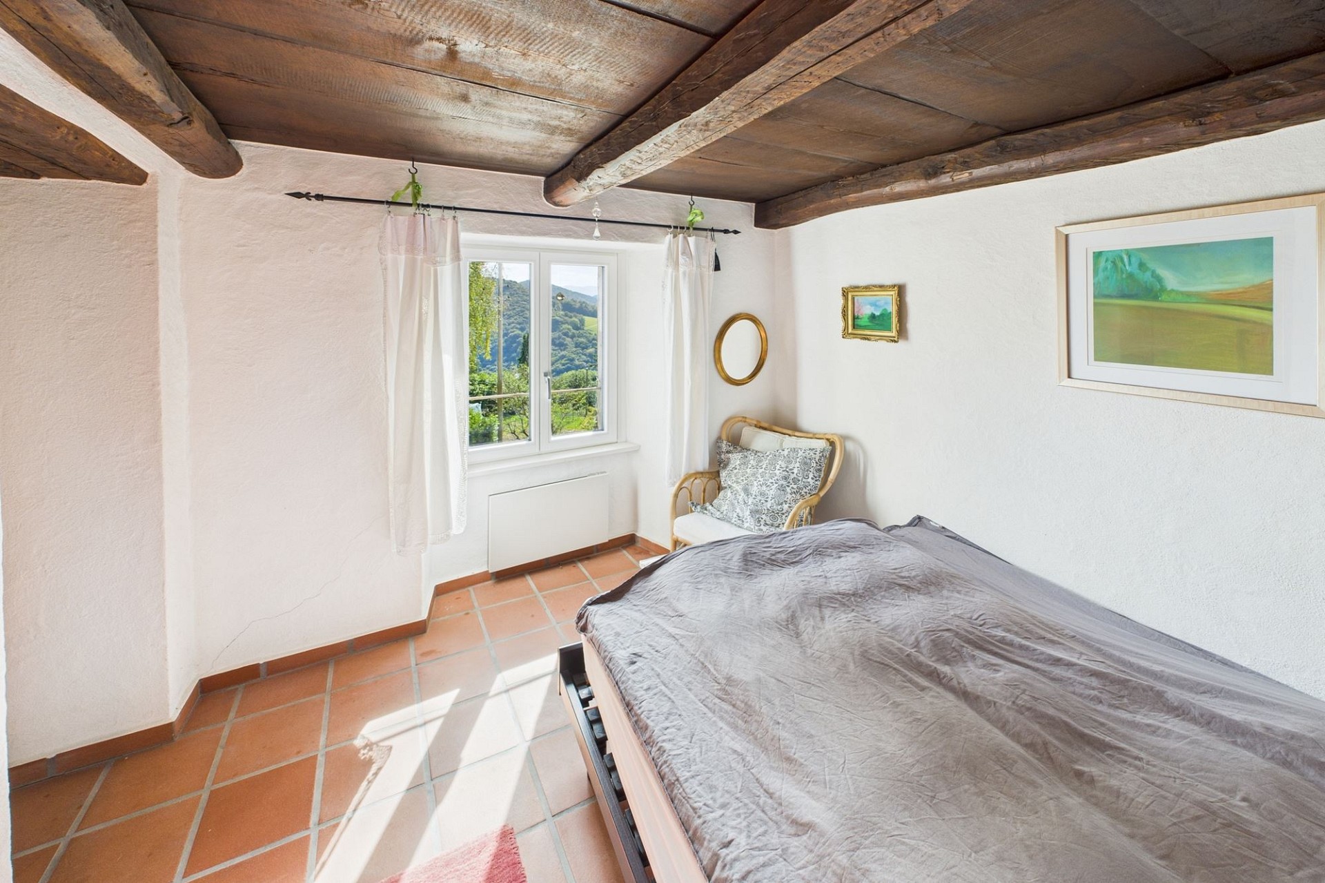 Gemütliches Schlafzimmer mit rustikalen Deckenbalken und Aussicht ins Grüne
