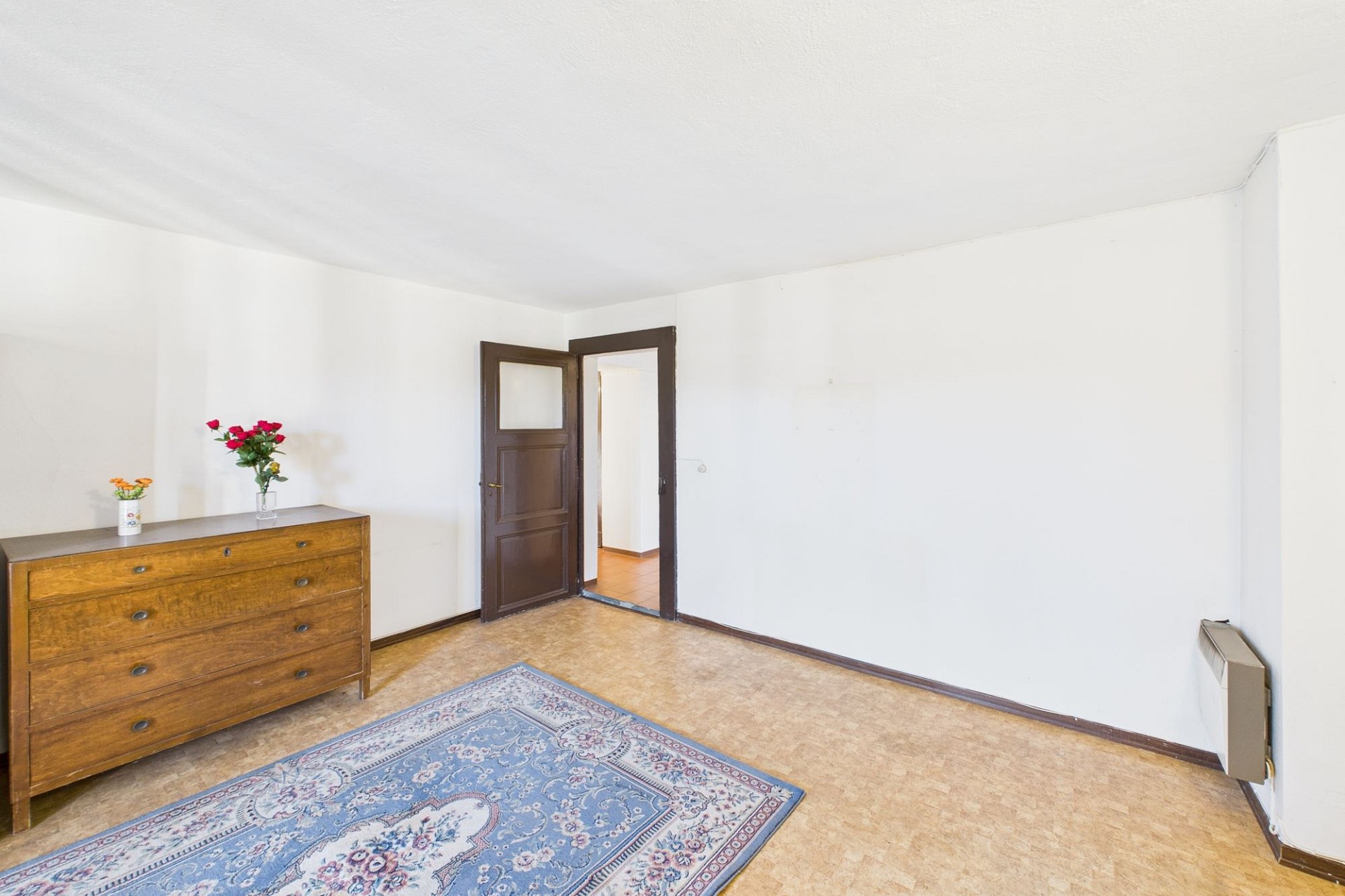 Leerer Wohnraum mit Teppich und Kommode