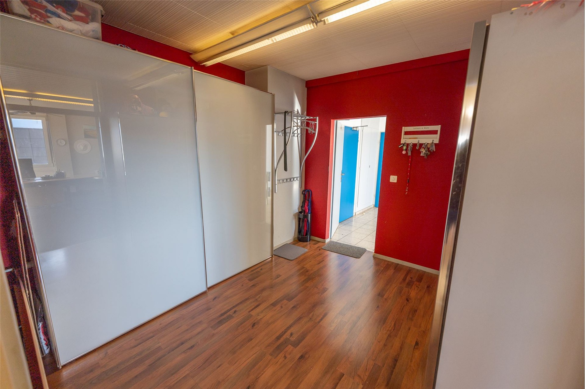 Modernes Zimmer mit roter Akzentwand und Schrankfronten