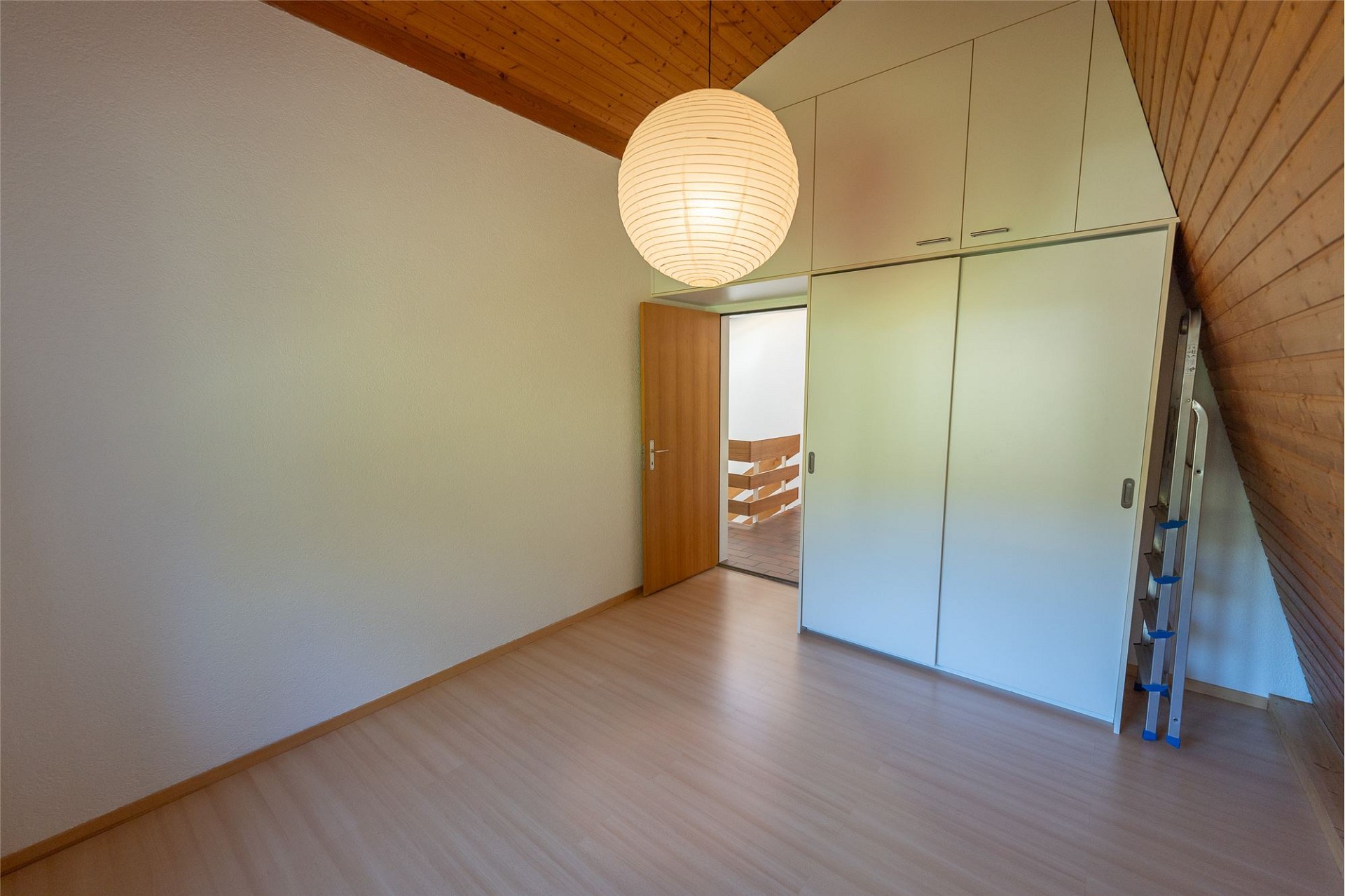 Dachgeschosszimmer mit Einbauschrank und Holzbalkendecke