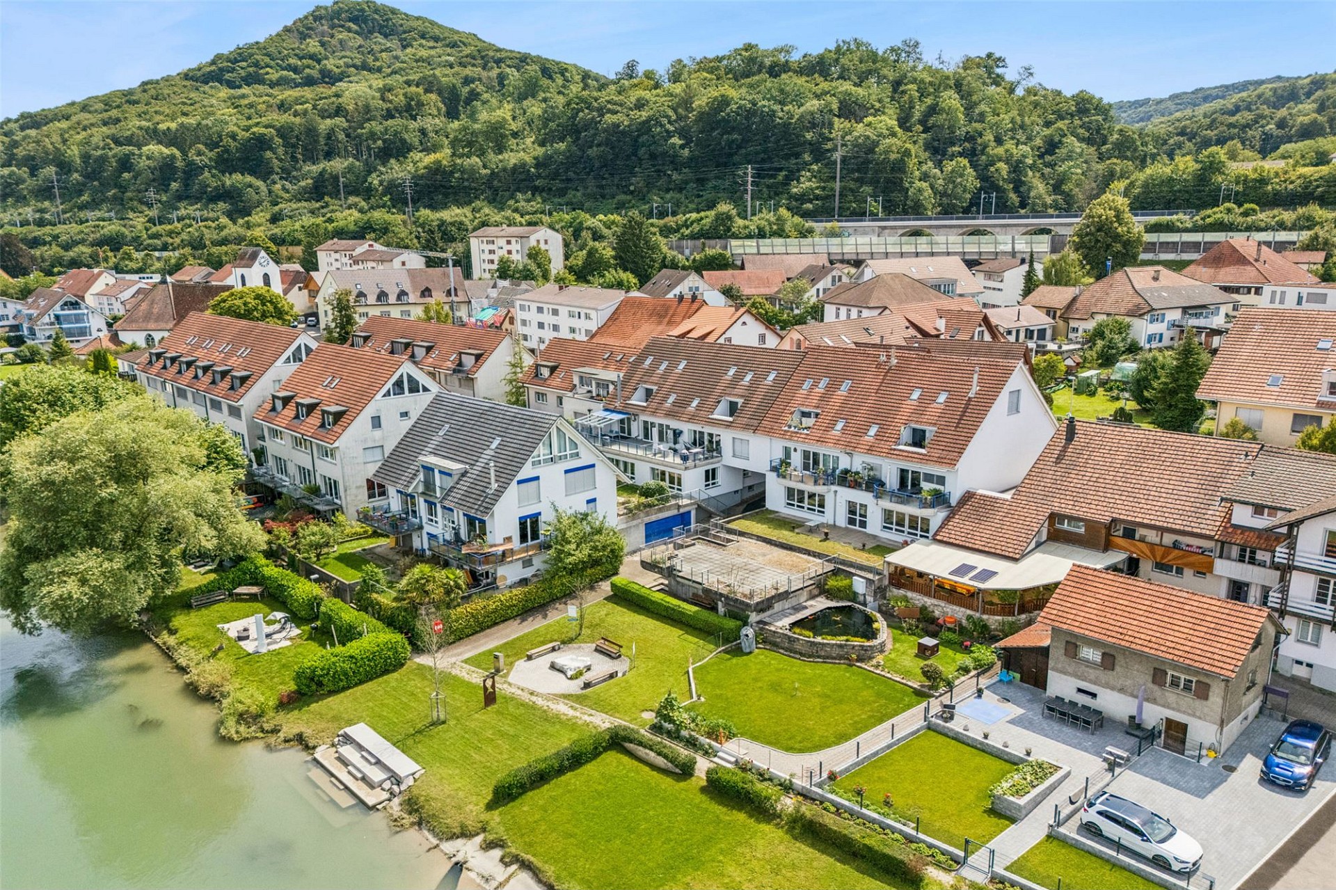 Luftaufnahme einer Wohnsiedlung am Wasser mit Bergen im Hintergrund