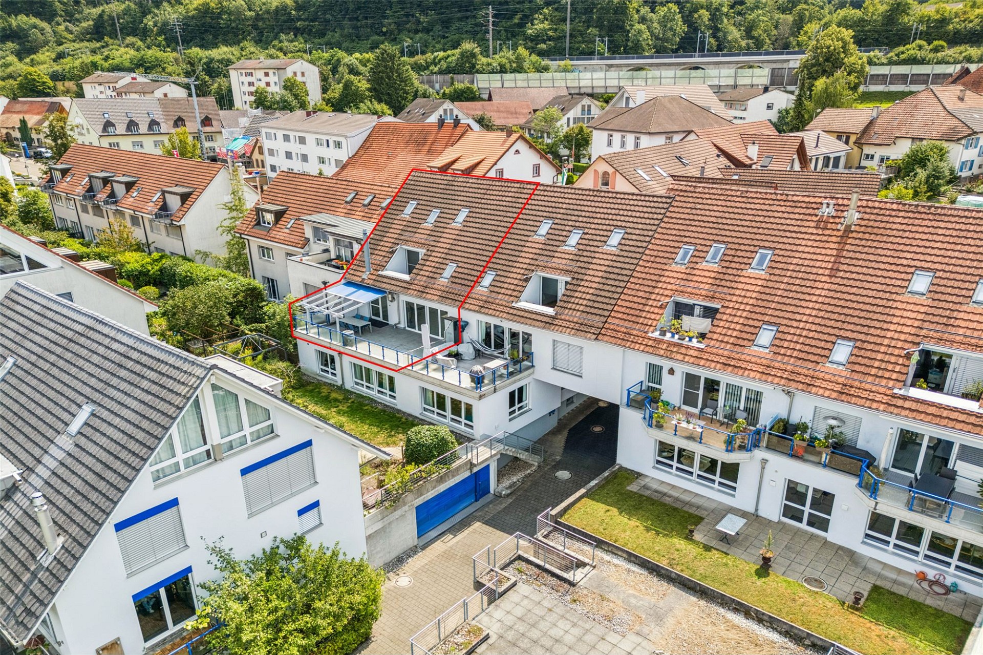 Drohnenaufnahme eines Wohngebiets mit markierter Dachwohnung und Balkon