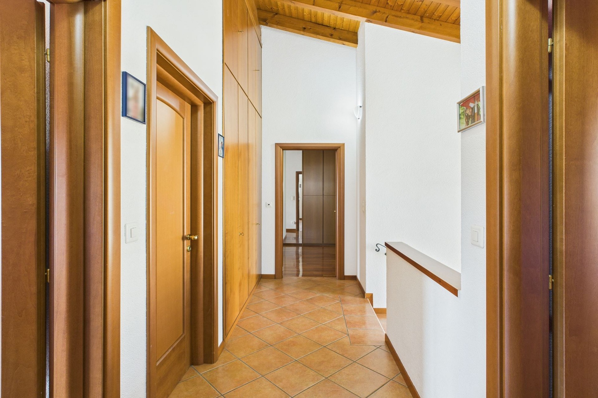 Heller Dachgeschoss-Flur mit Holztreppe und Fliesenboden