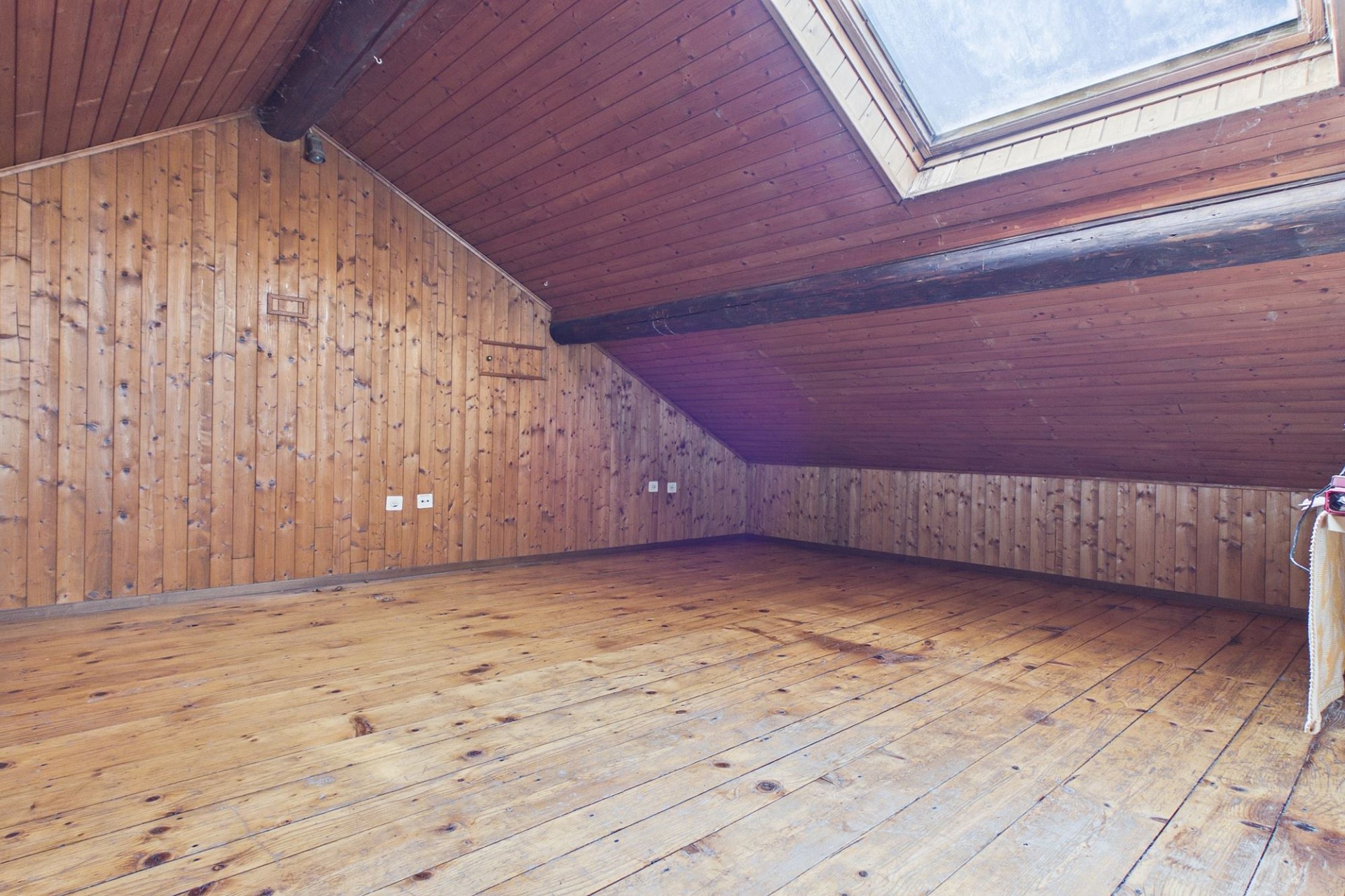 Leerer Dachraum mit Holzverkleidung und Dachfenster