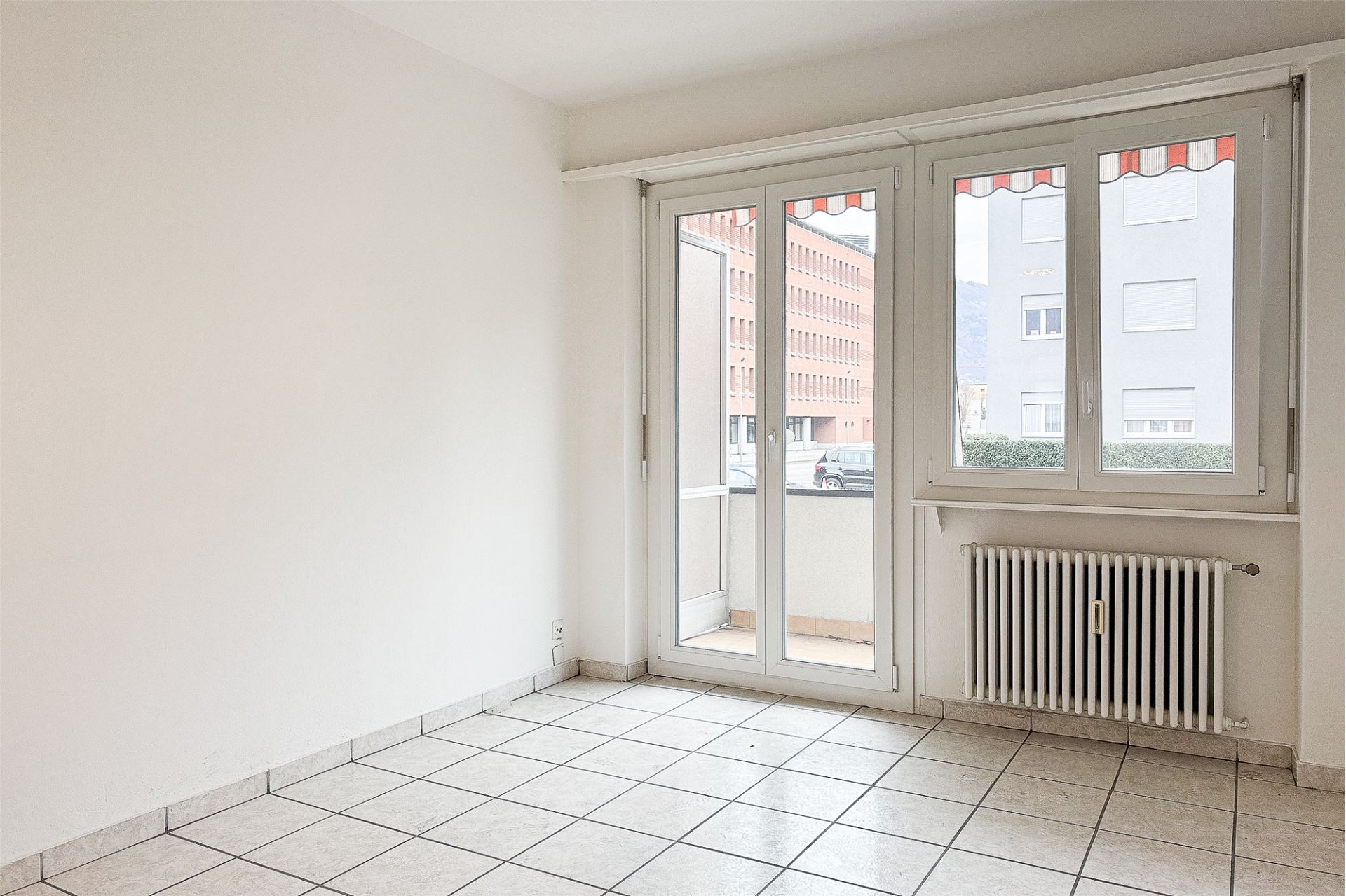 Heller leerer Wohnraum mit Balkon und Heizkörper