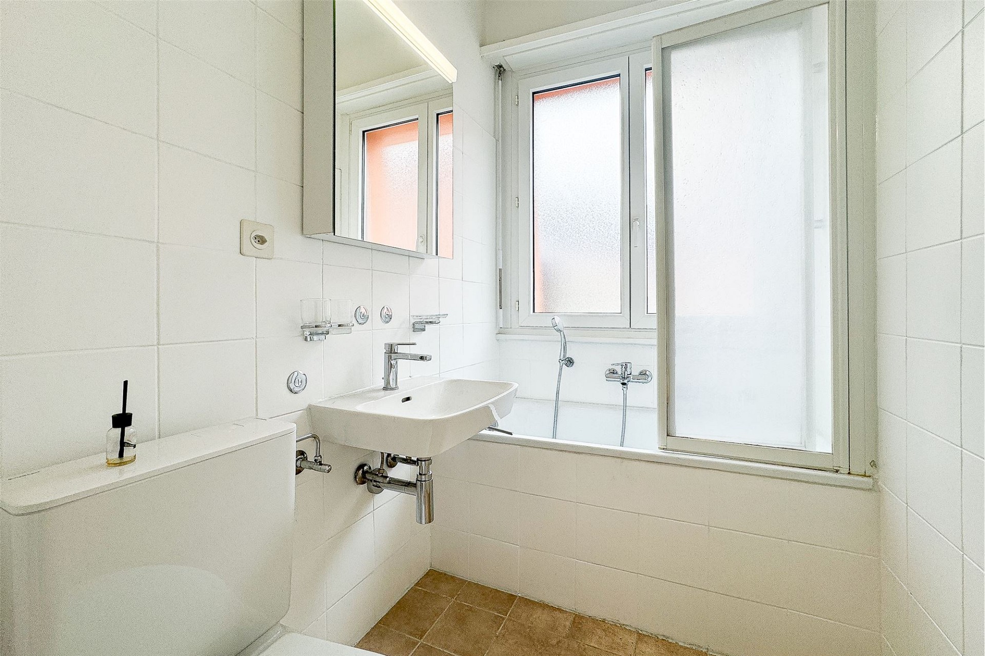 Kleines weiß gefliestes Badezimmer mit Fenster