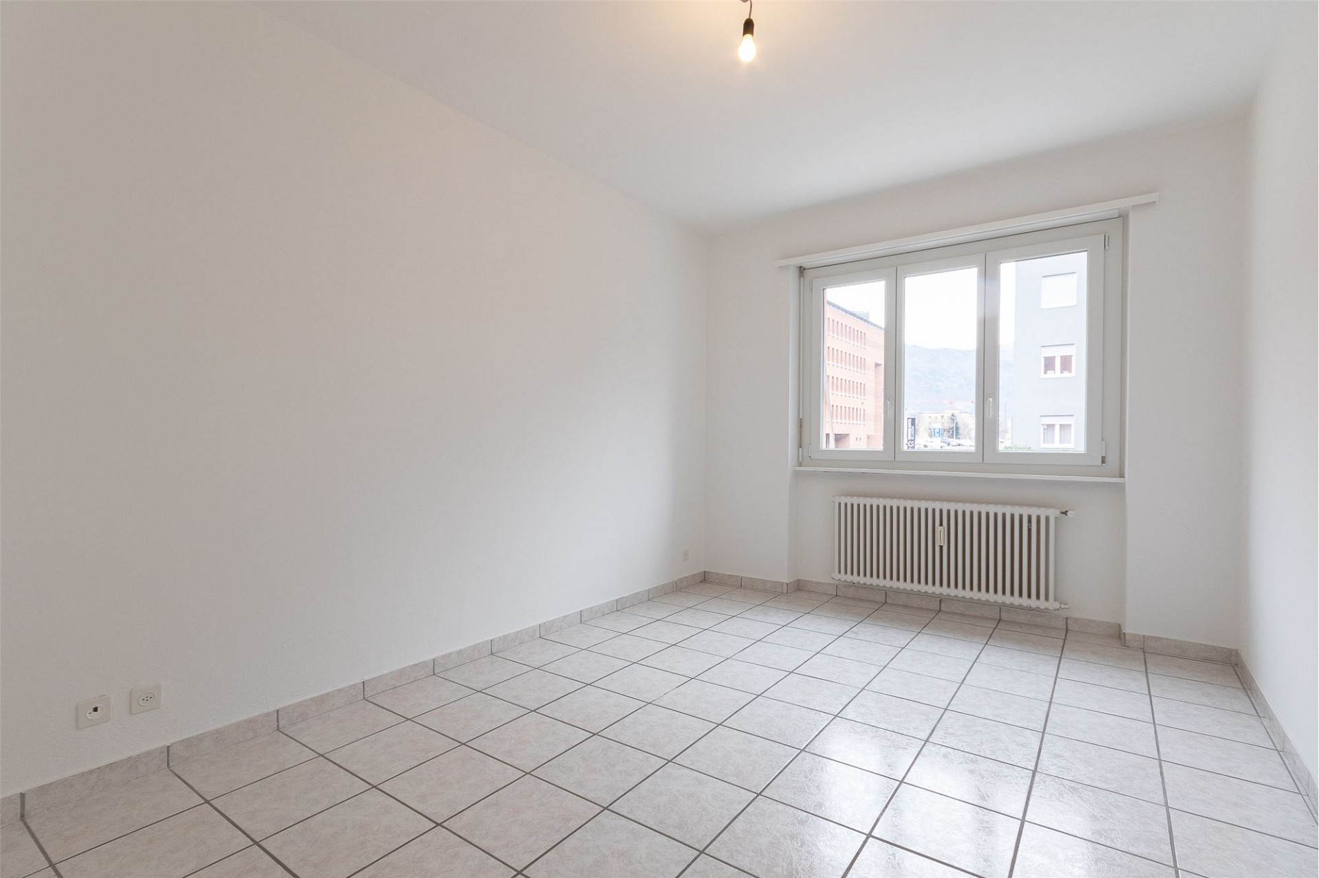 Helles, leeres Zimmer mit Fliesenboden und Fenster