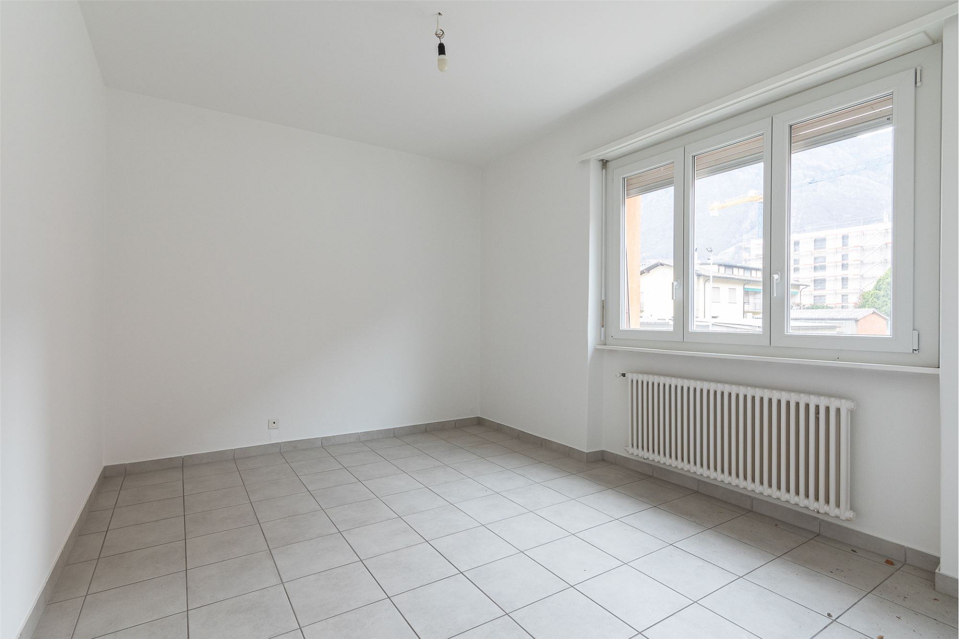 Leerer, heller Raum mit Fenster und Heizkörper