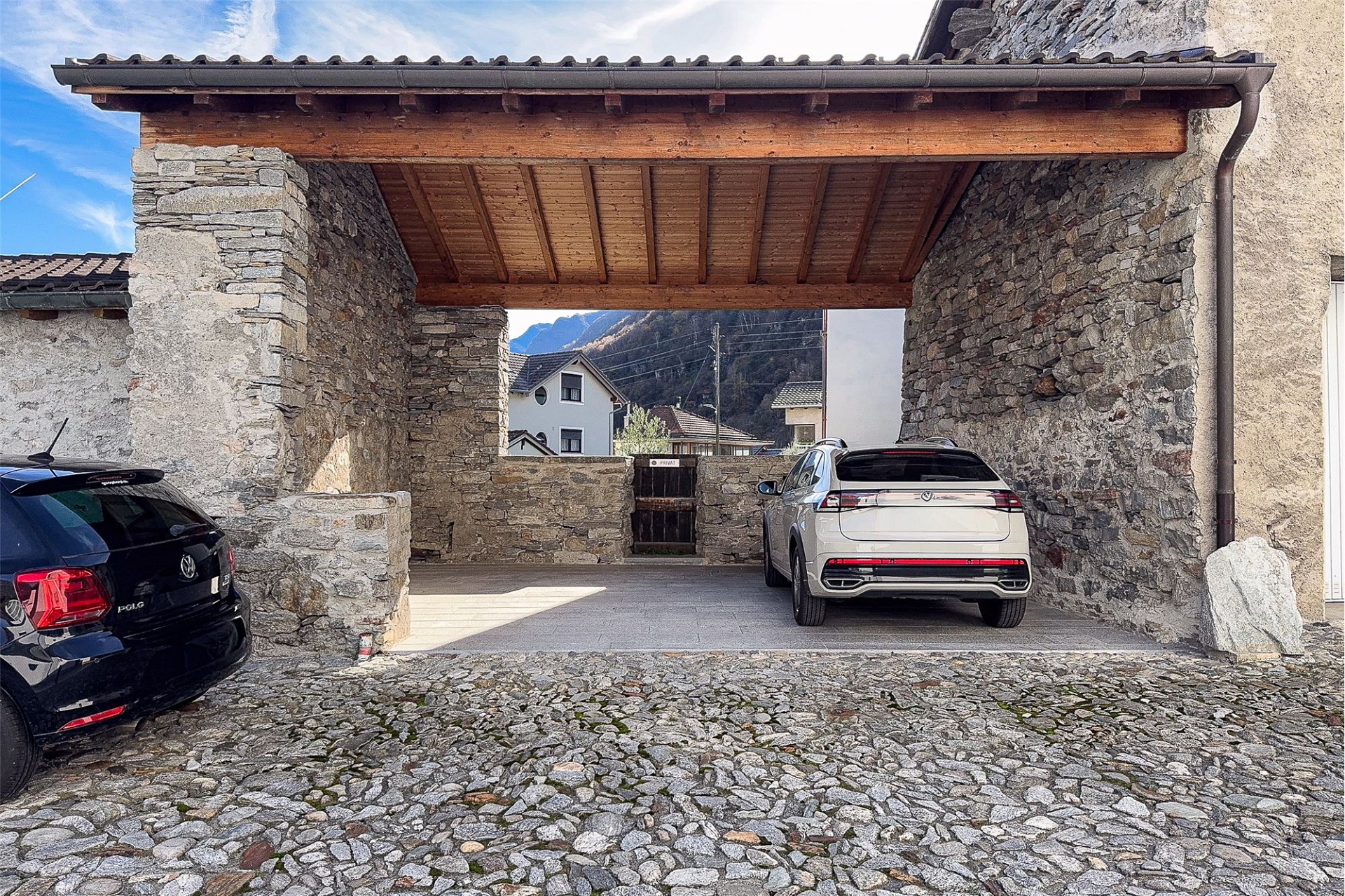 Überdachter Stein-Carport mit zwei geparkten Autos