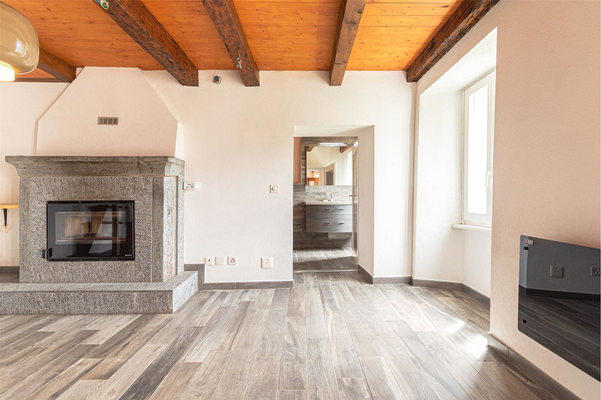 Wohnraum mit Kamin und sichtbaren Holzbalken