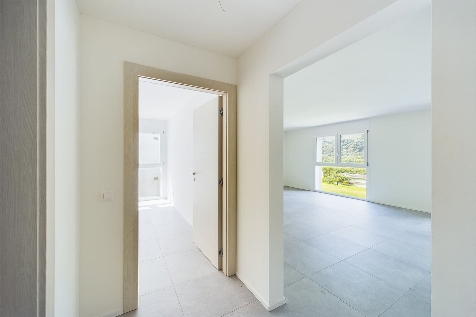 Heller, moderner Flur mit Blick in einen leeren Wohnraum