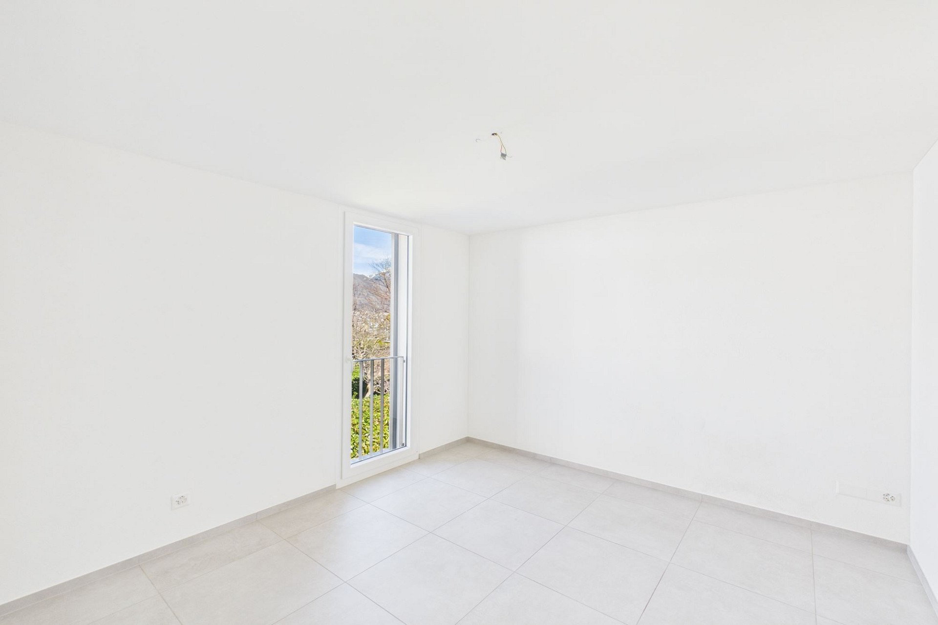 Leerer, heller Raum mit Fliesenboden und schmalem Fenster